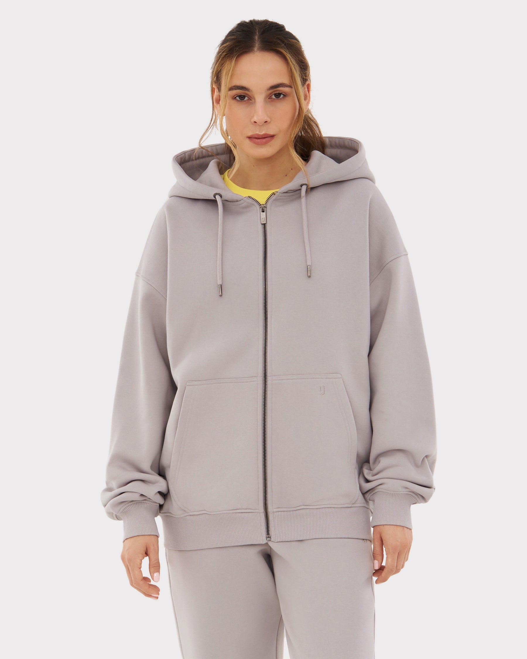 Frau trägt oversized Zip Hoodie ‚Caleb‘ in Grau mit Kapuze und Kängurutaschen