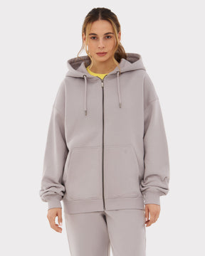 Frau trägt oversized Zip Hoodie ‚Caleb‘ in Grau mit Kapuze und Kängurutaschen