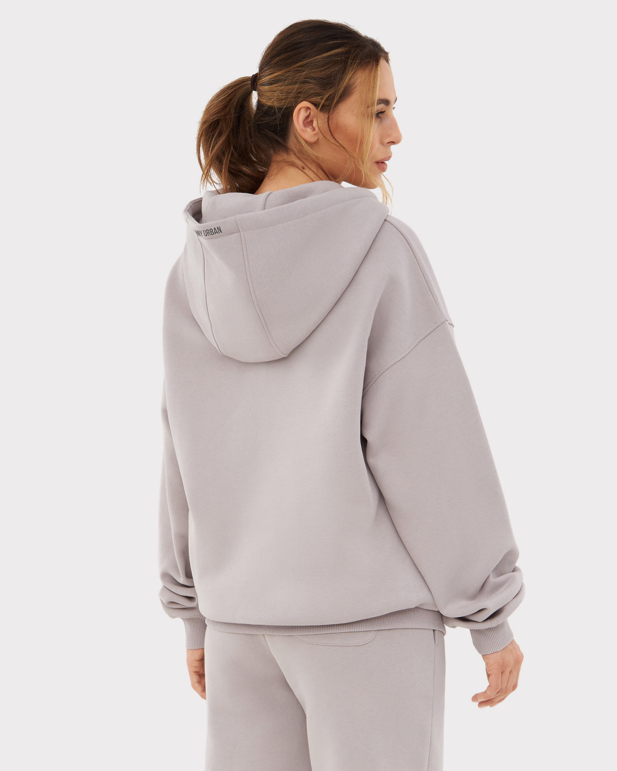 Frau von hinten in oversized Zip Hoodie 'Caleb' in graubeige mit Kapuze, entspanntem Schnitt und langen Ärmeln