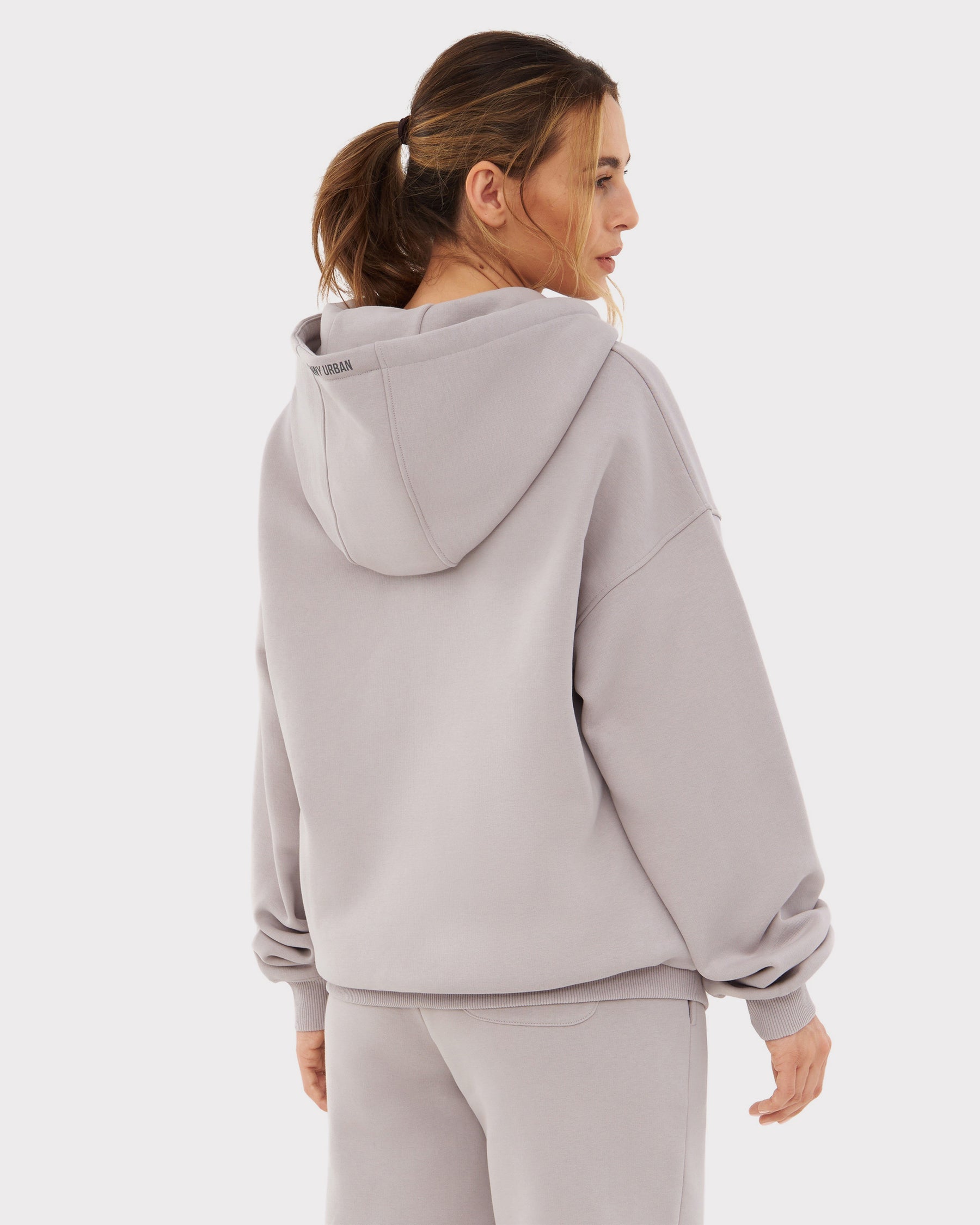 Frau von hinten in oversized Zip Hoodie 'Caleb' in graubeige mit Kapuze, entspanntem Schnitt und langen Ärmeln