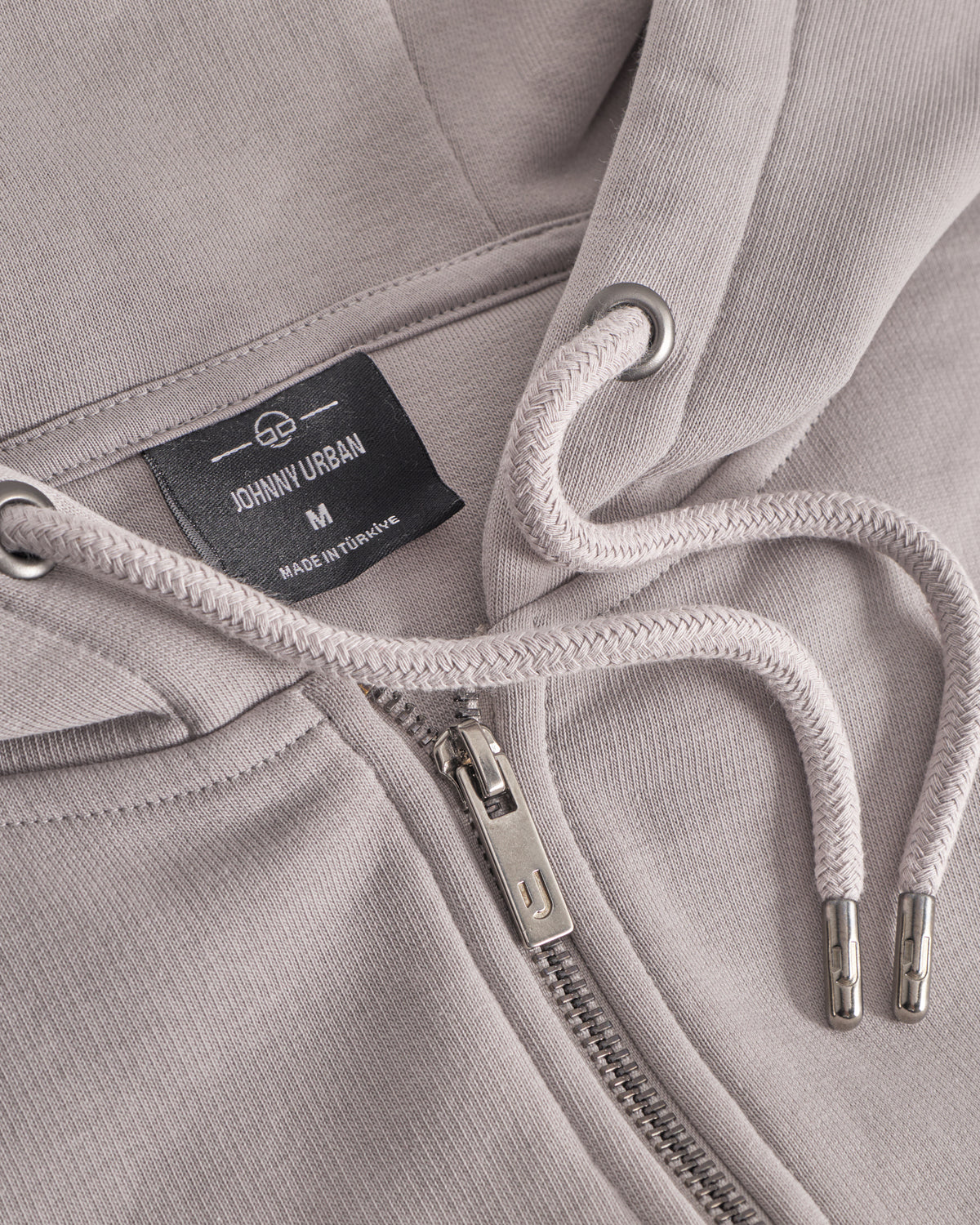Detailansicht des Kapuzenzugs und Reißverschlusses der oversized Zip Hoodie 'Caleb' in Beige von Johnny Urban
