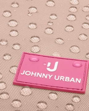 Nahaufnahme eines wasserabweisenden Materials mit zwei Wassertropfen auf einem rosa Johnny Urban Junior Etikett