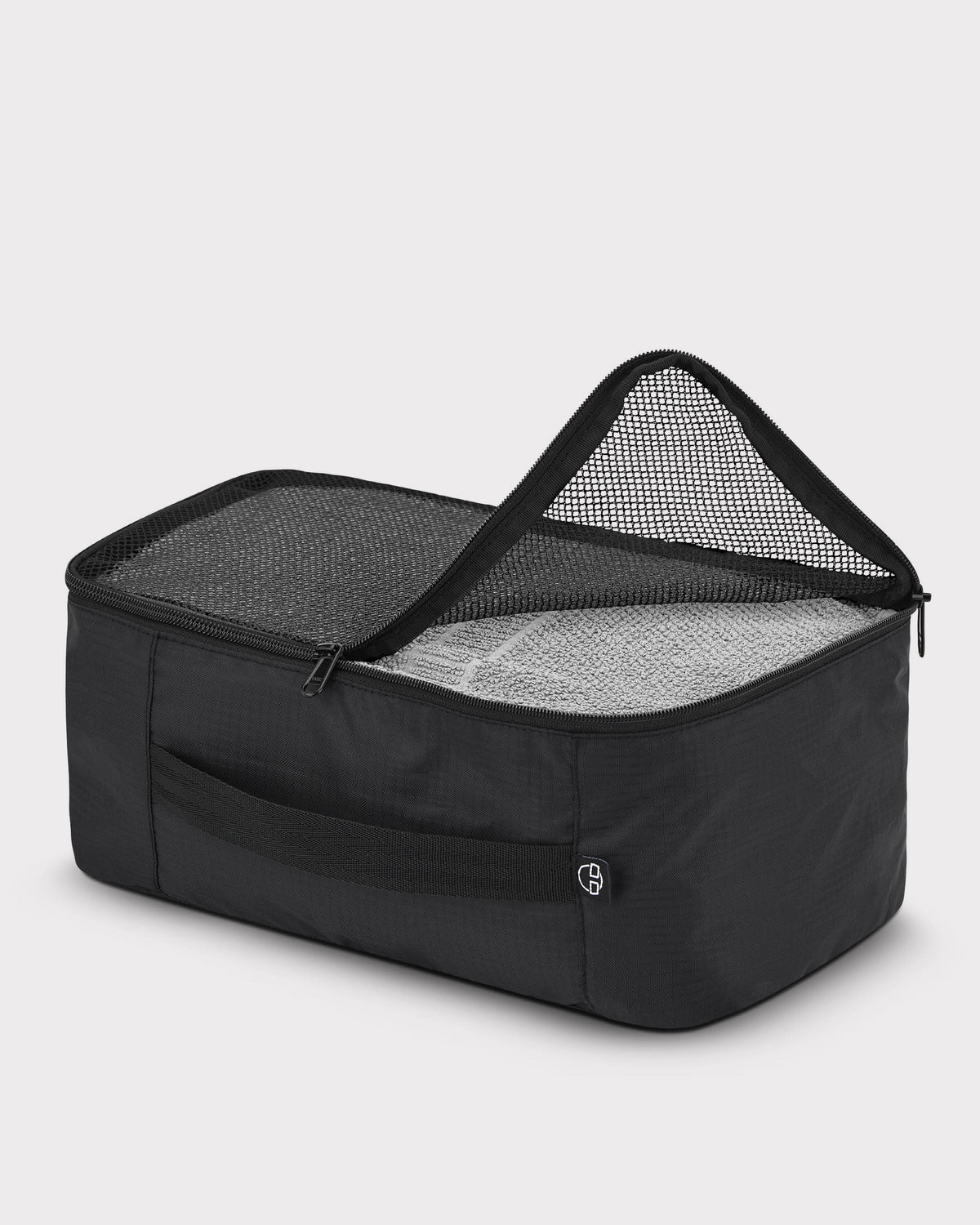 Schwarze Kleidertasche ‚Zack‘ von Johnny Urban mit Netzabdeckung, teilweise geöffnet, gefüllt mit einem grauen Handtuch