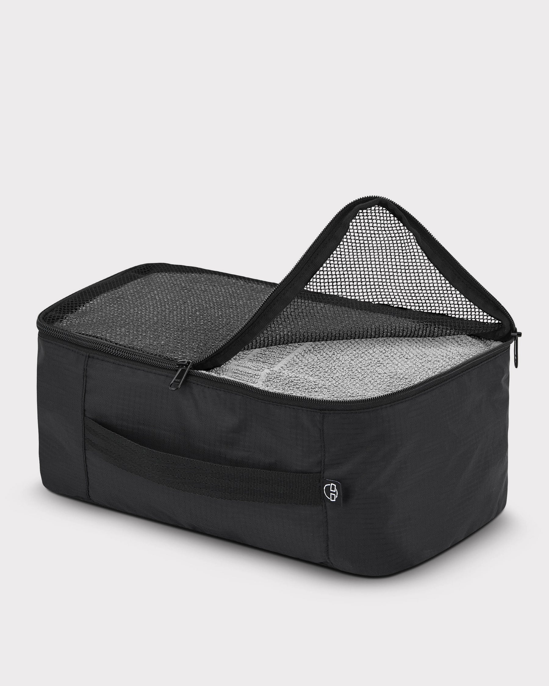 Schwarze Kleidertasche ‚Zack‘ von Johnny Urban mit Netzabdeckung, teilweise geöffnet, gefüllt mit einem grauen Handtuch