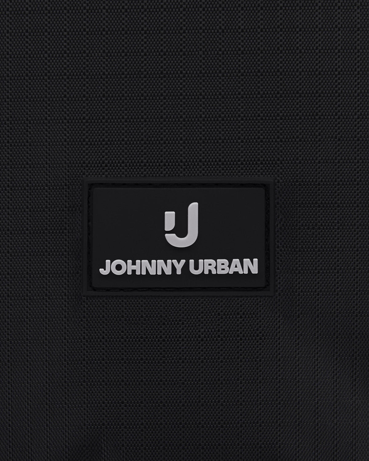 Nahaufnahme des Johnny Urban Logos auf schwarzem Stoff einer Kulturtasche