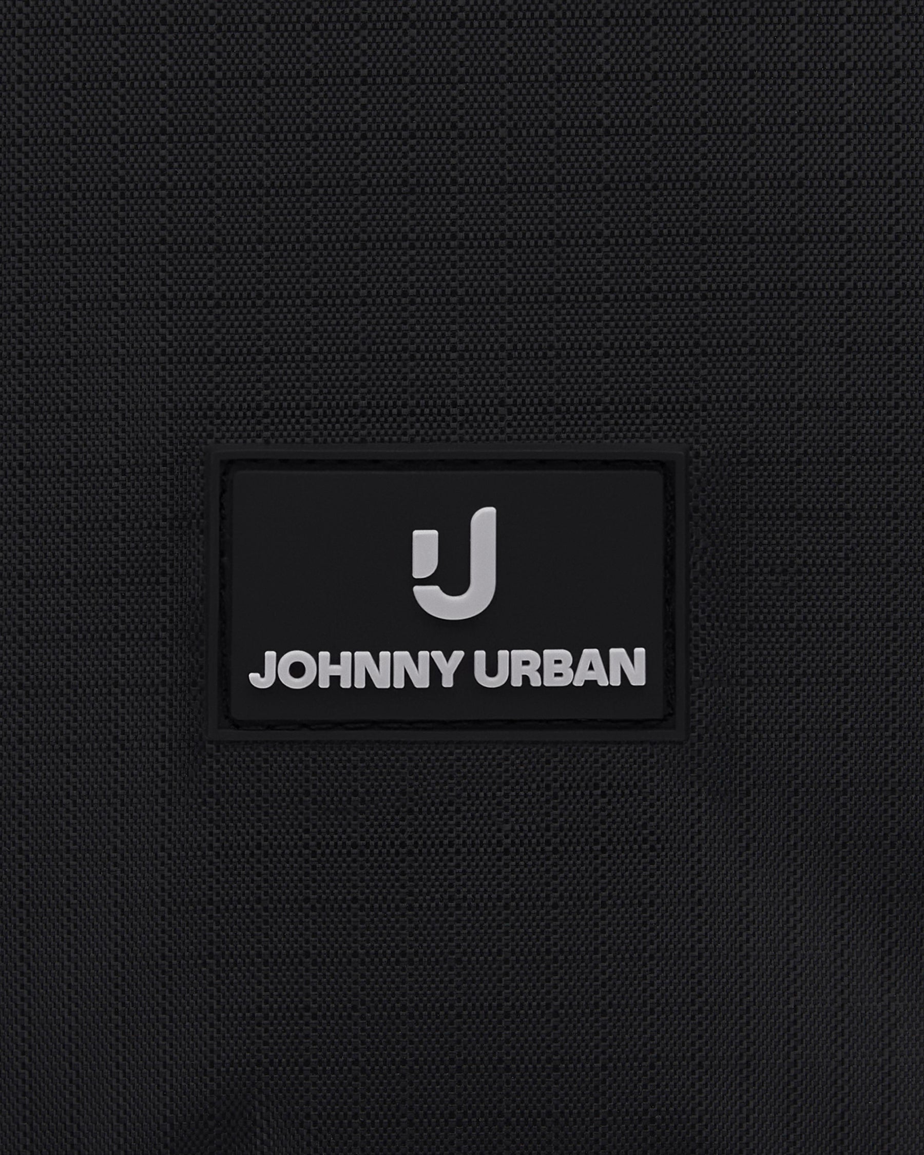 Nahaufnahme des Johnny Urban Logos auf schwarzem Stoff einer Kulturtasche