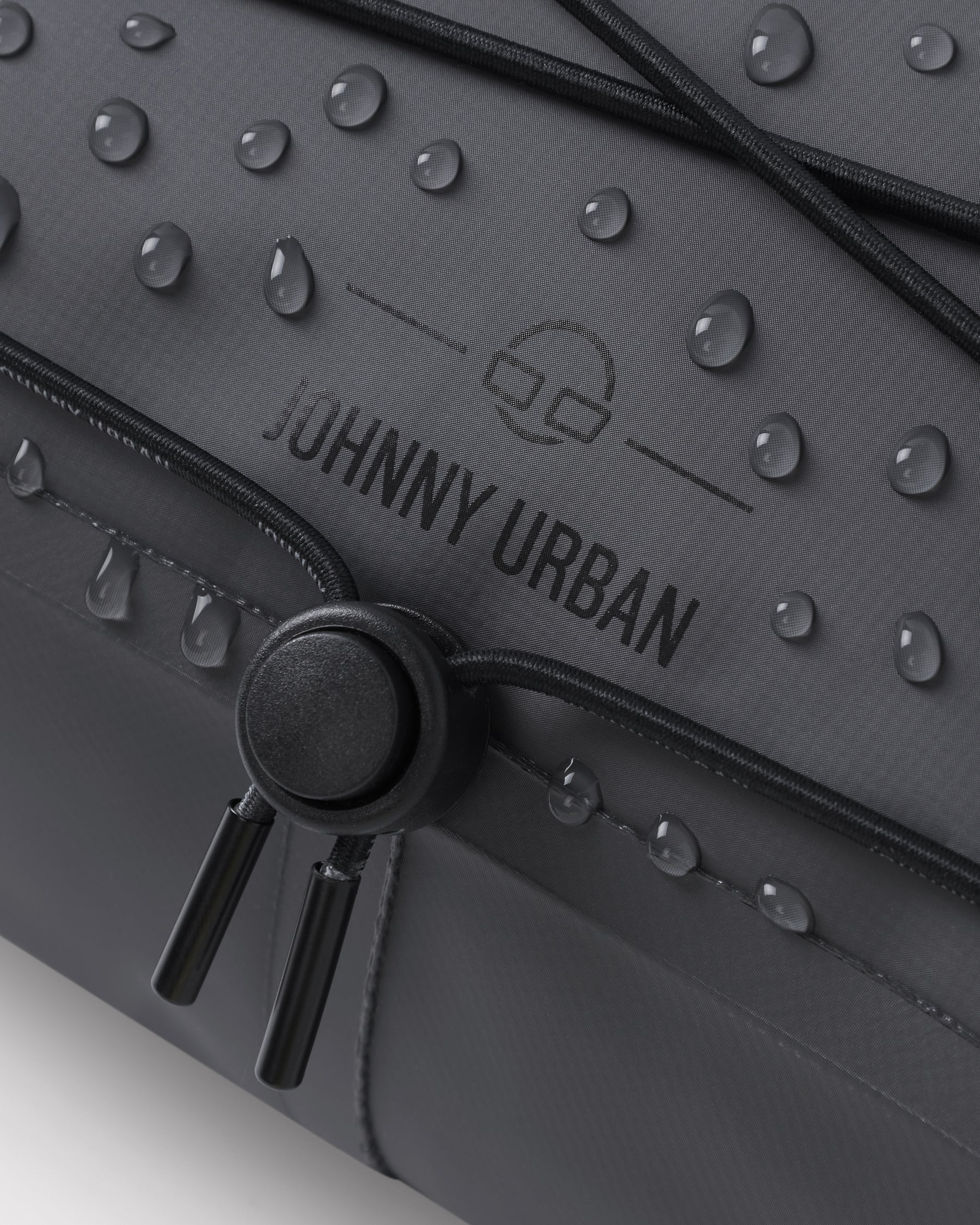 Naheinstellung der schwarzen Lenkertasche 'Arlo' von Johnny Urban mit Wasserperlen auf der Oberfläche