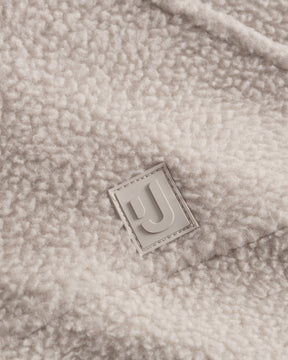 Unser hochwertiges Logo-Badge auf der Fleecejacke Nova in Beige.  