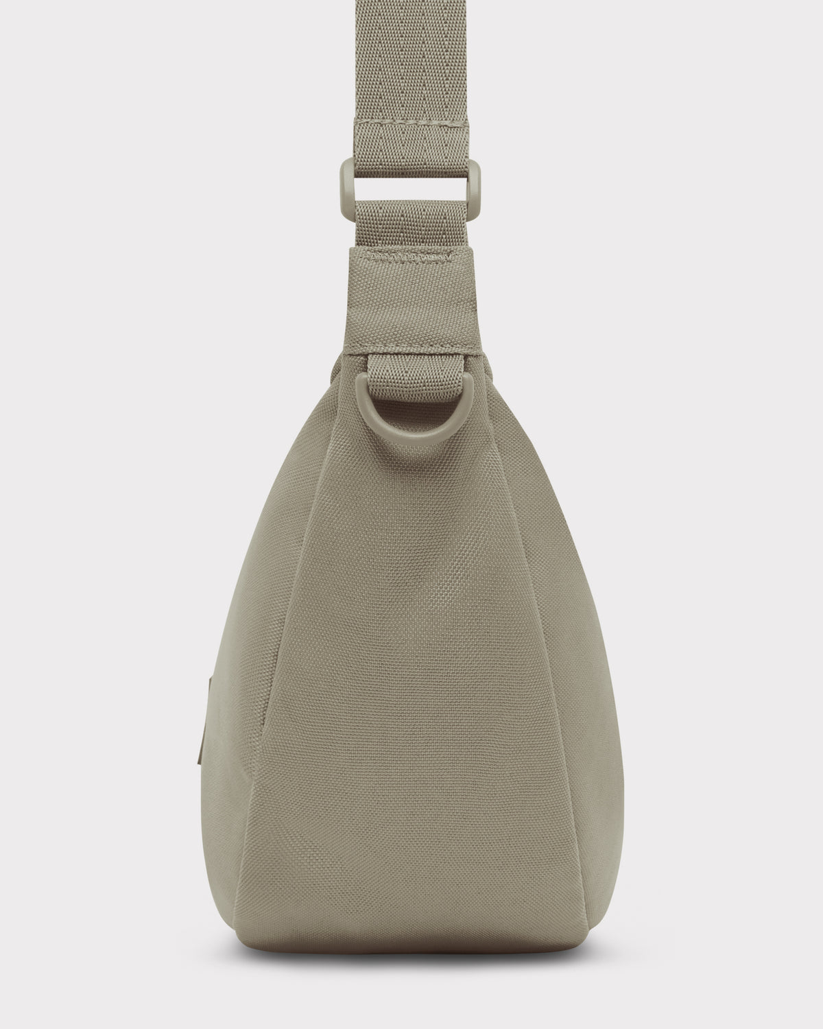 Seitenansicht der halbmondförmigen Tasche ‚Ally Medium‘ in Beige mit gepolstertem Trageriemen und D-Ring