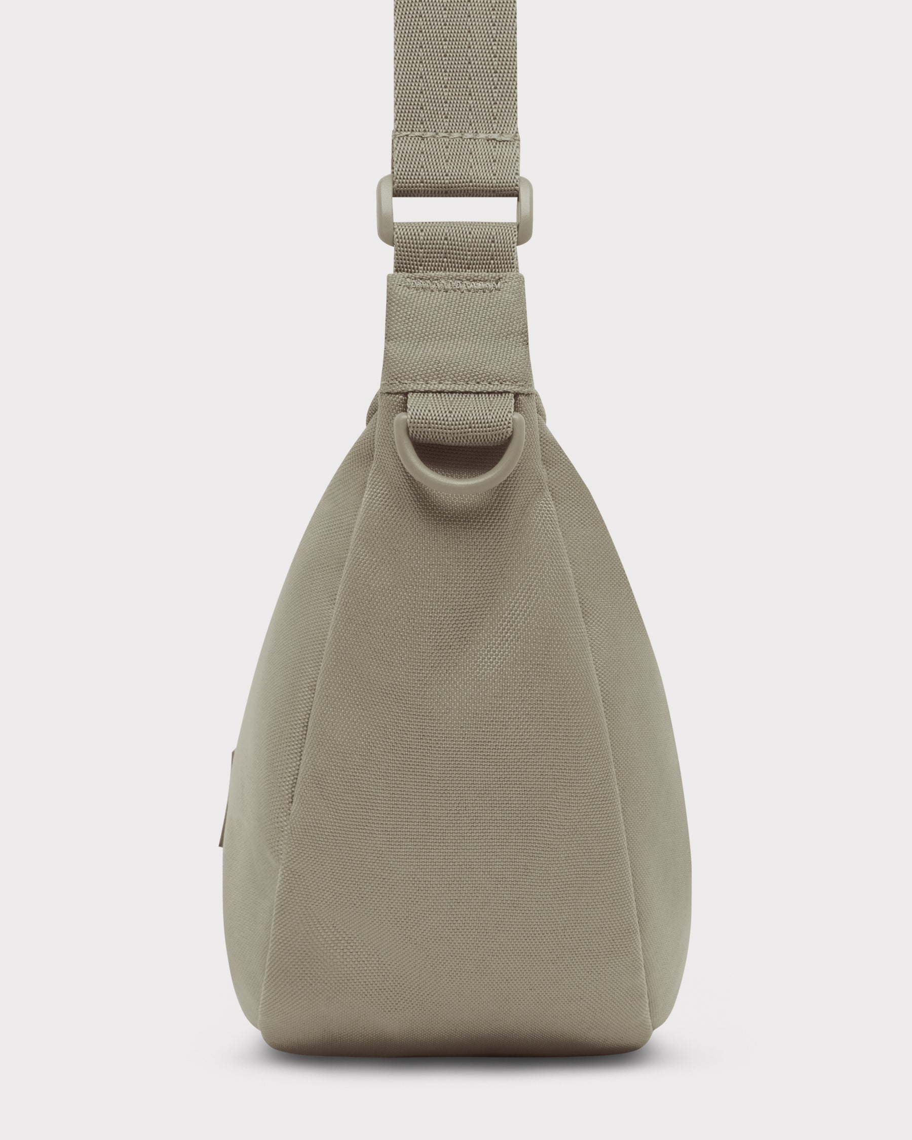Seitenansicht der halbmondförmigen Tasche ‚Ally Medium‘ in Beige mit gepolstertem Trageriemen und D-Ring