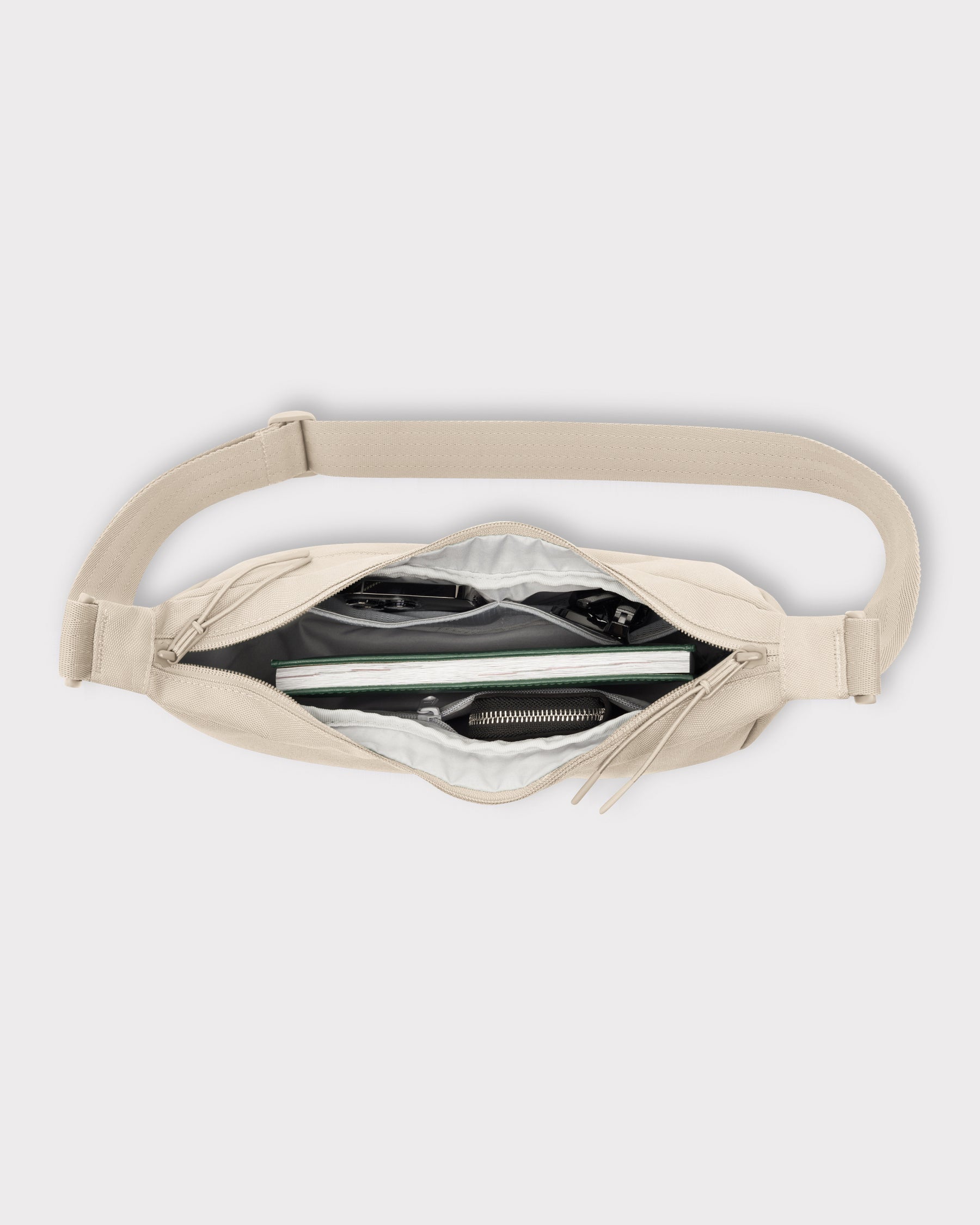 Geöffnete halbmondförmige Tasche Ally Medium in Beige mit sichtbaren Innenfächern und Inhalt