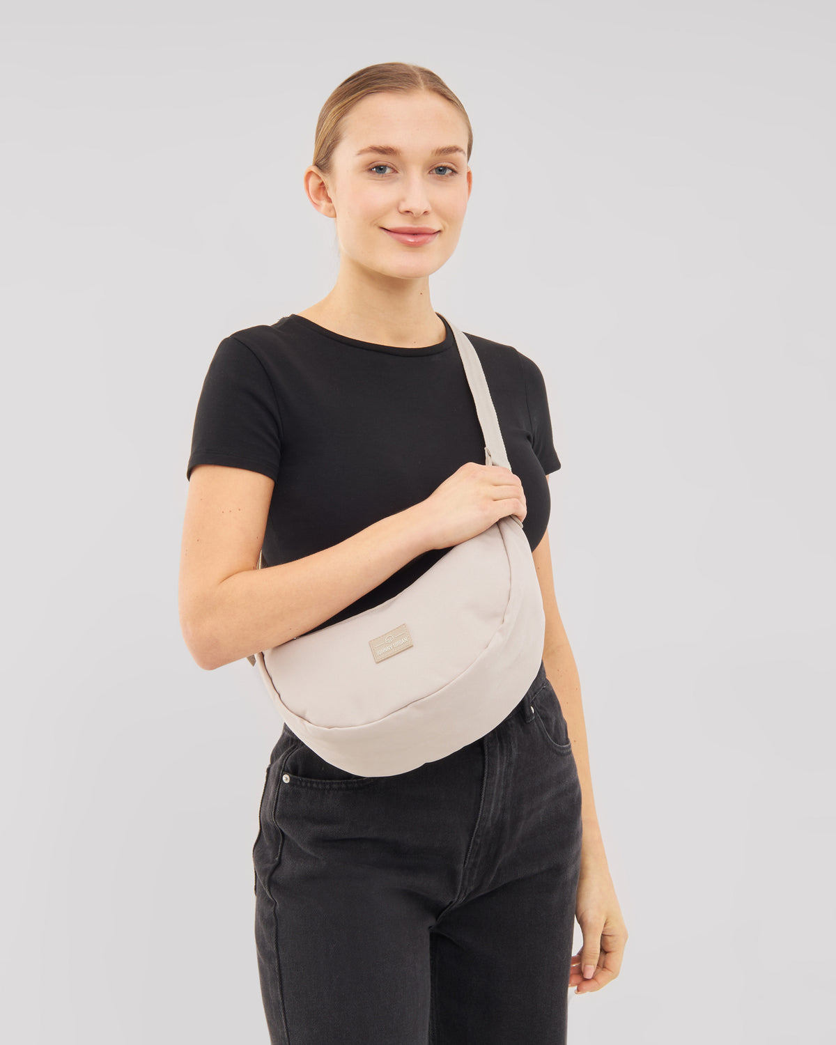 Frau trägt die beige Half Moon Bag 'Ally Medium' von Johnny Urban über der Schulter