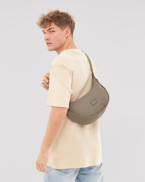 Mann trägt die Half Moon Bag 'Ally Medium' von Johnny Urban in taupe über der Schulter