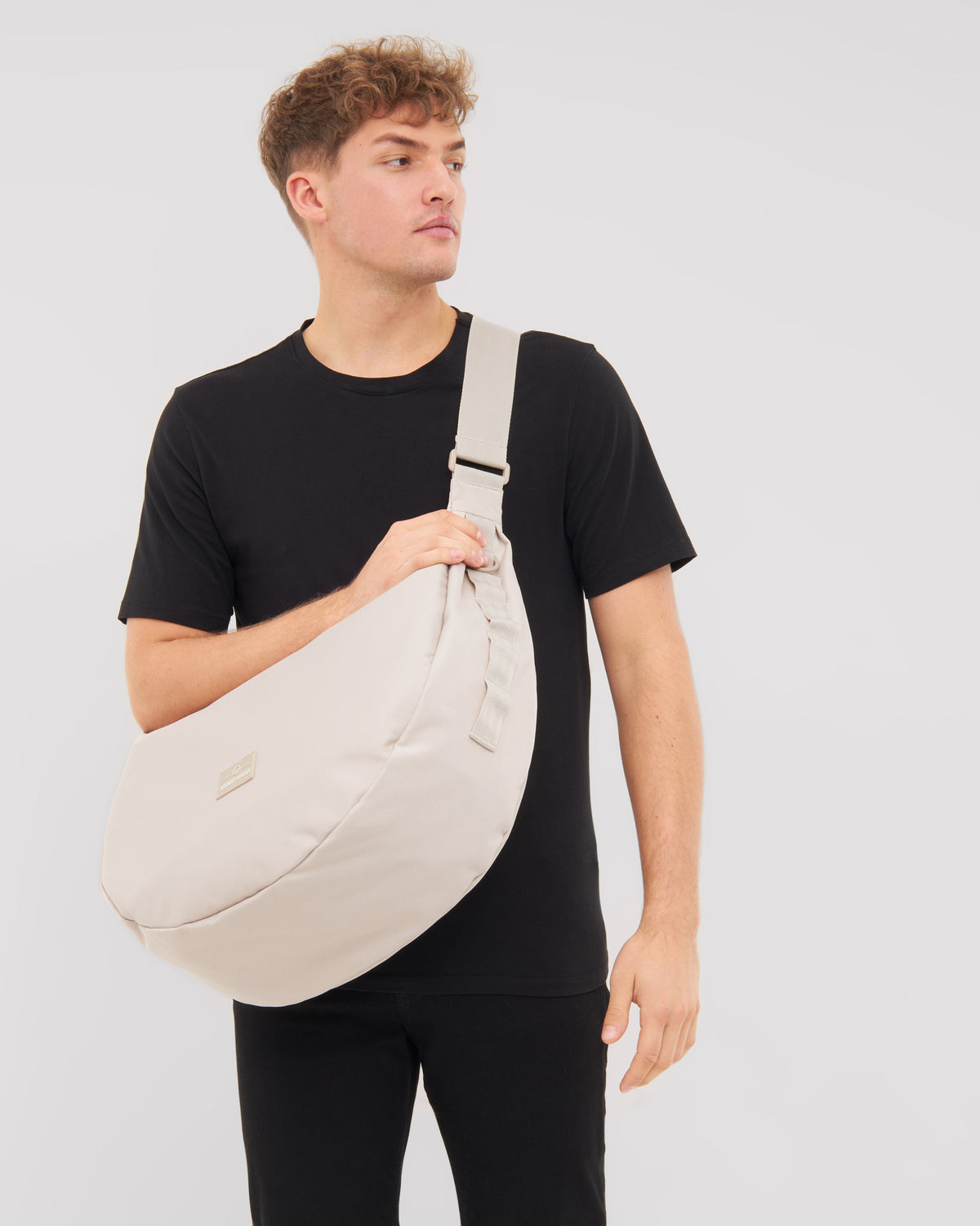 Mann trägt halbmondförmige Tasche 'Ally XL' in Beige quer über den Oberkörper