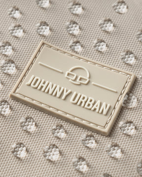 Nahaufnahme des Johnny Urban Logos auf wasserabweisendem hellbeigem Stoff mit Wassertropfen