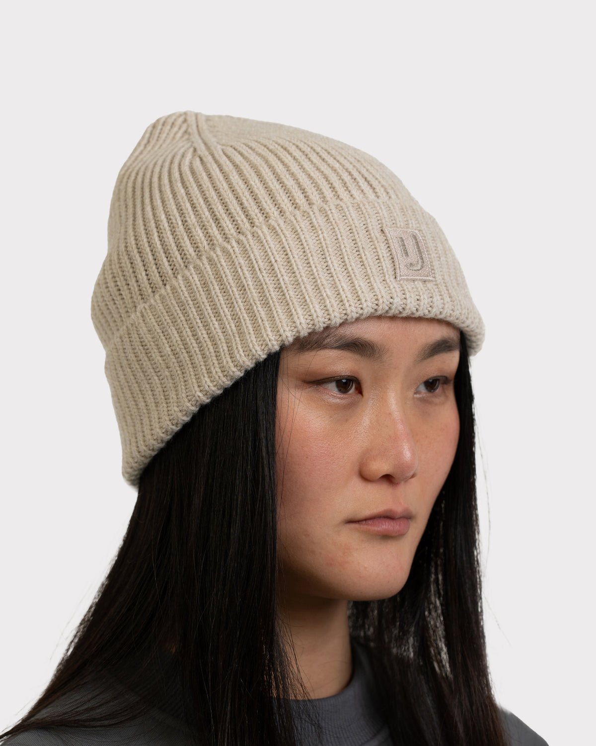 Beige gestrickte Mütze 'Billie' von Johnny Urban an Frau mit langen schwarzen Haaren