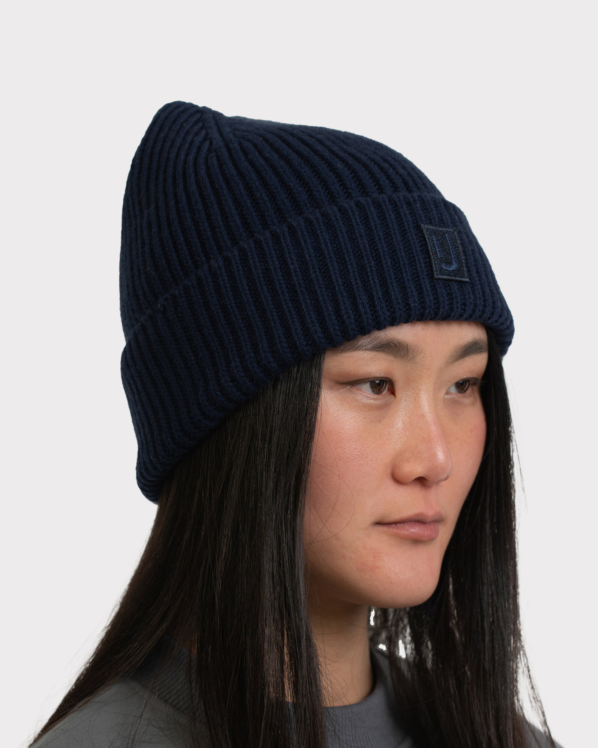 Dunkelblaue gerippte Beanie 'Billie' von Johnny Urban, getragen von einer Frau mit langen schwarzen Haaren