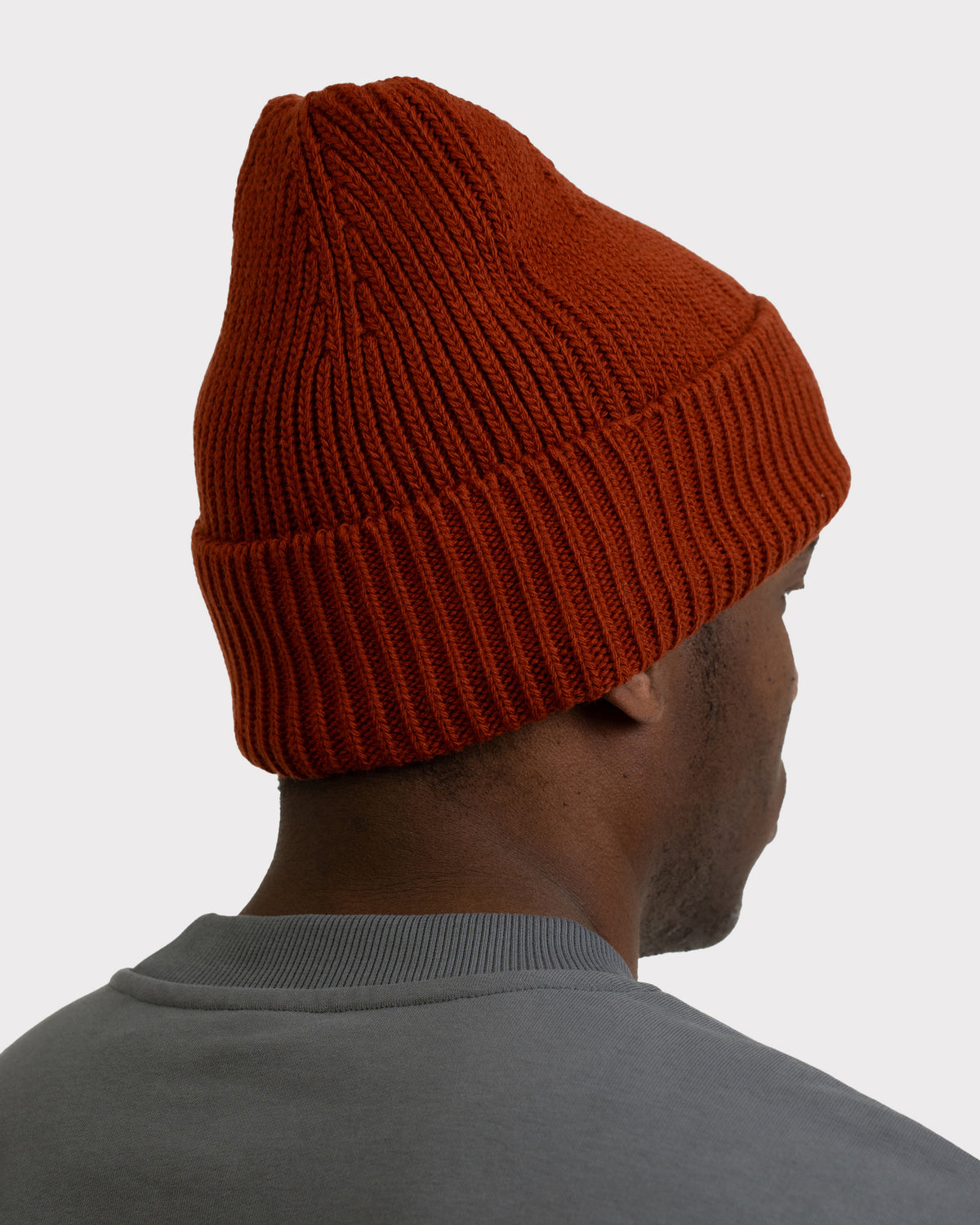Männliches Modell von hinten mit rostroter Strickmütze 'Billie' von Johnny Urban und grauem Pullover