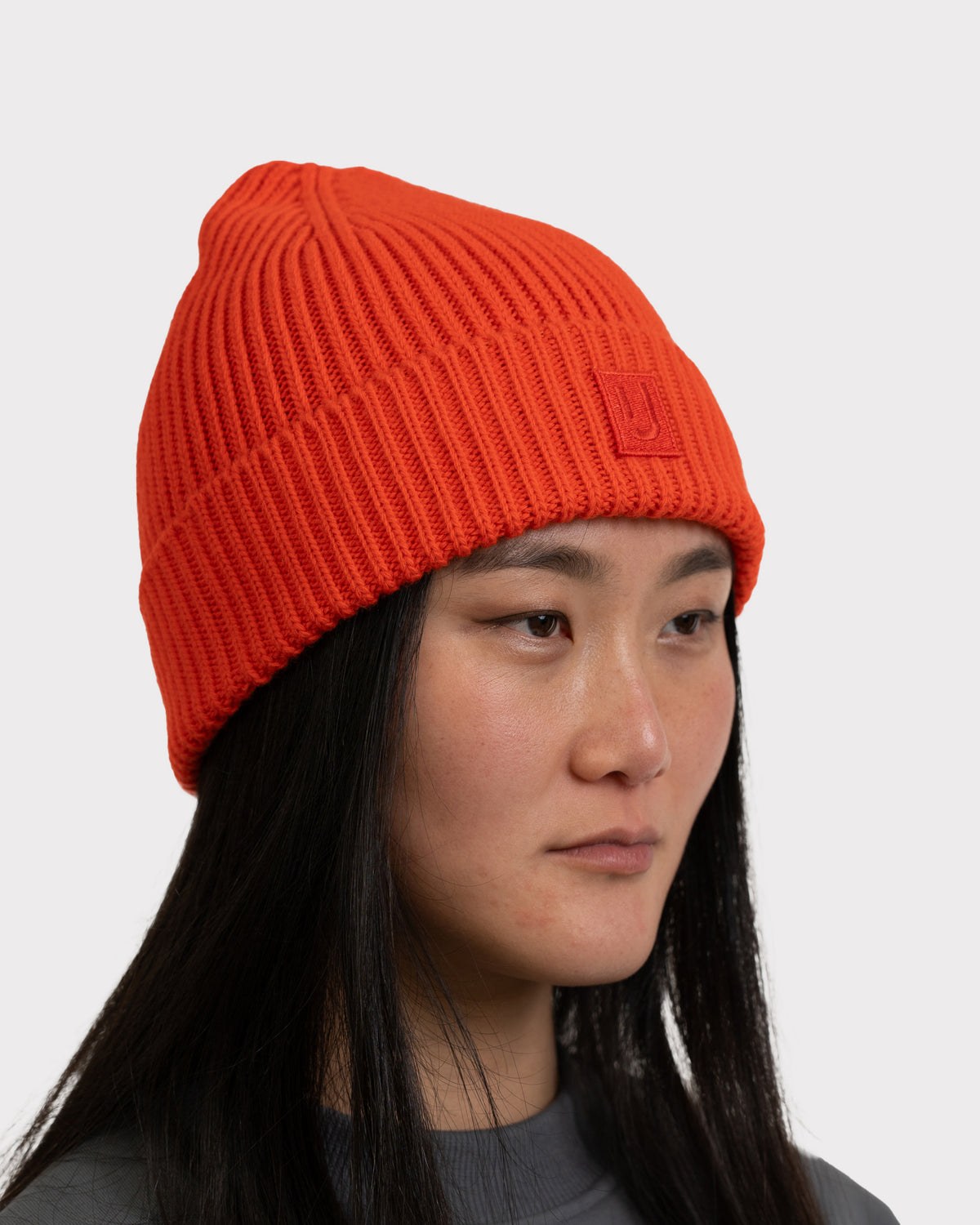 Dame trägt orange-rote, gerippte Strickmütze 'Billie' von Johnny Urban