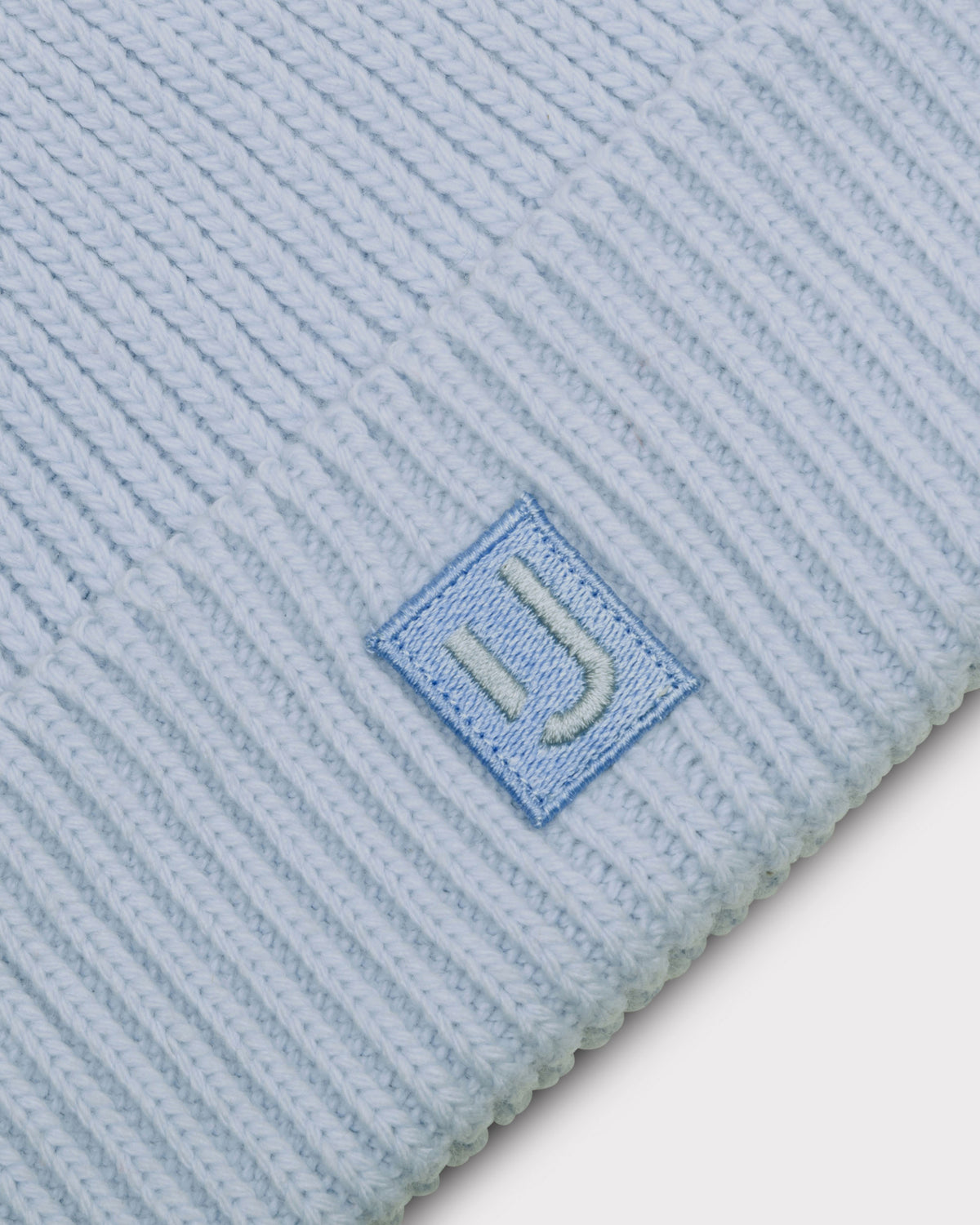 Hellblaue gerippte Strickmütze „Billie“ mit einem kleinen quadratischen Patch mit ‚JU‘-Logo