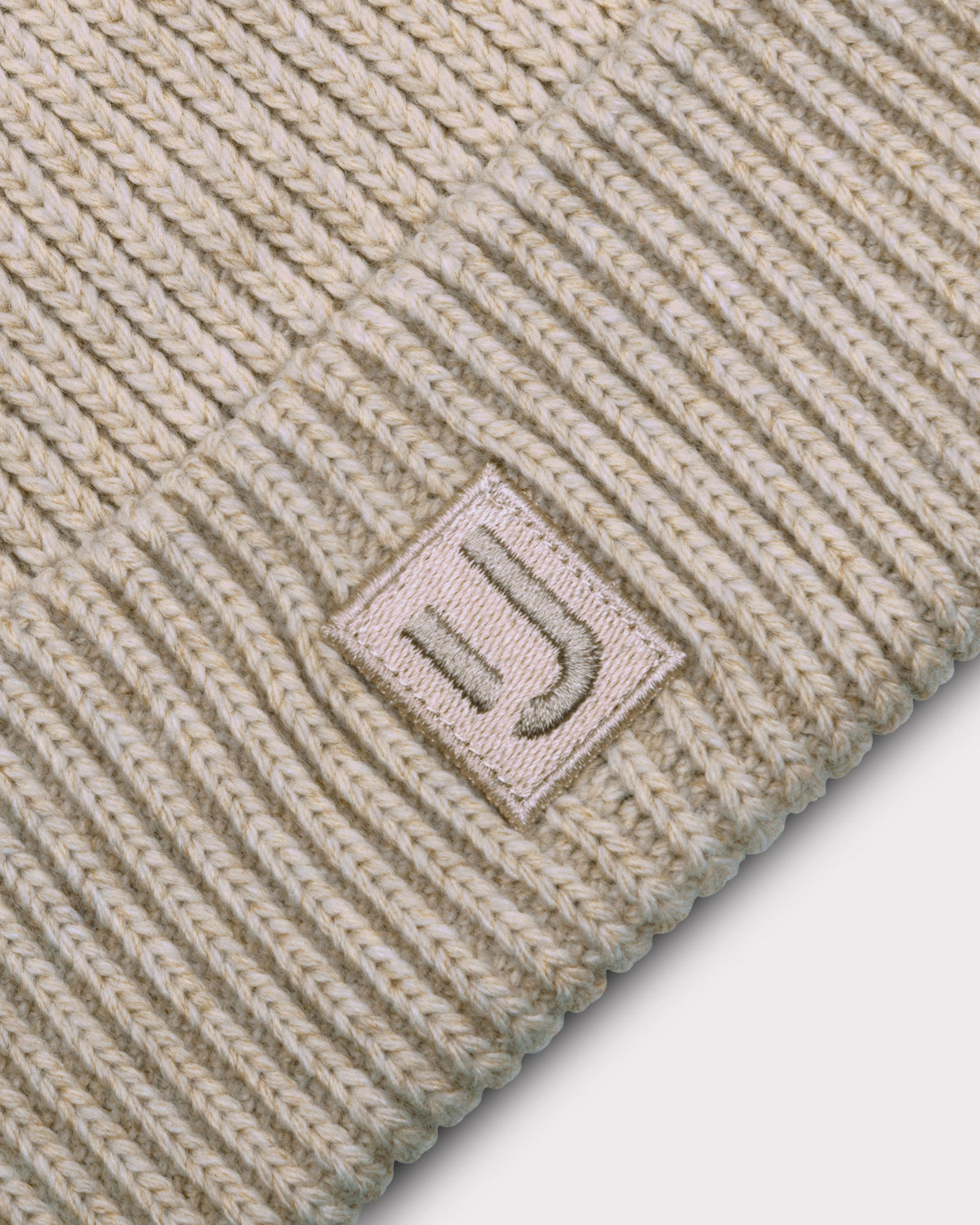 Beige gestrickte Mütze 'Billie' von Johnny Urban mit Label, das ein stilisiertes 'JU' zeigt