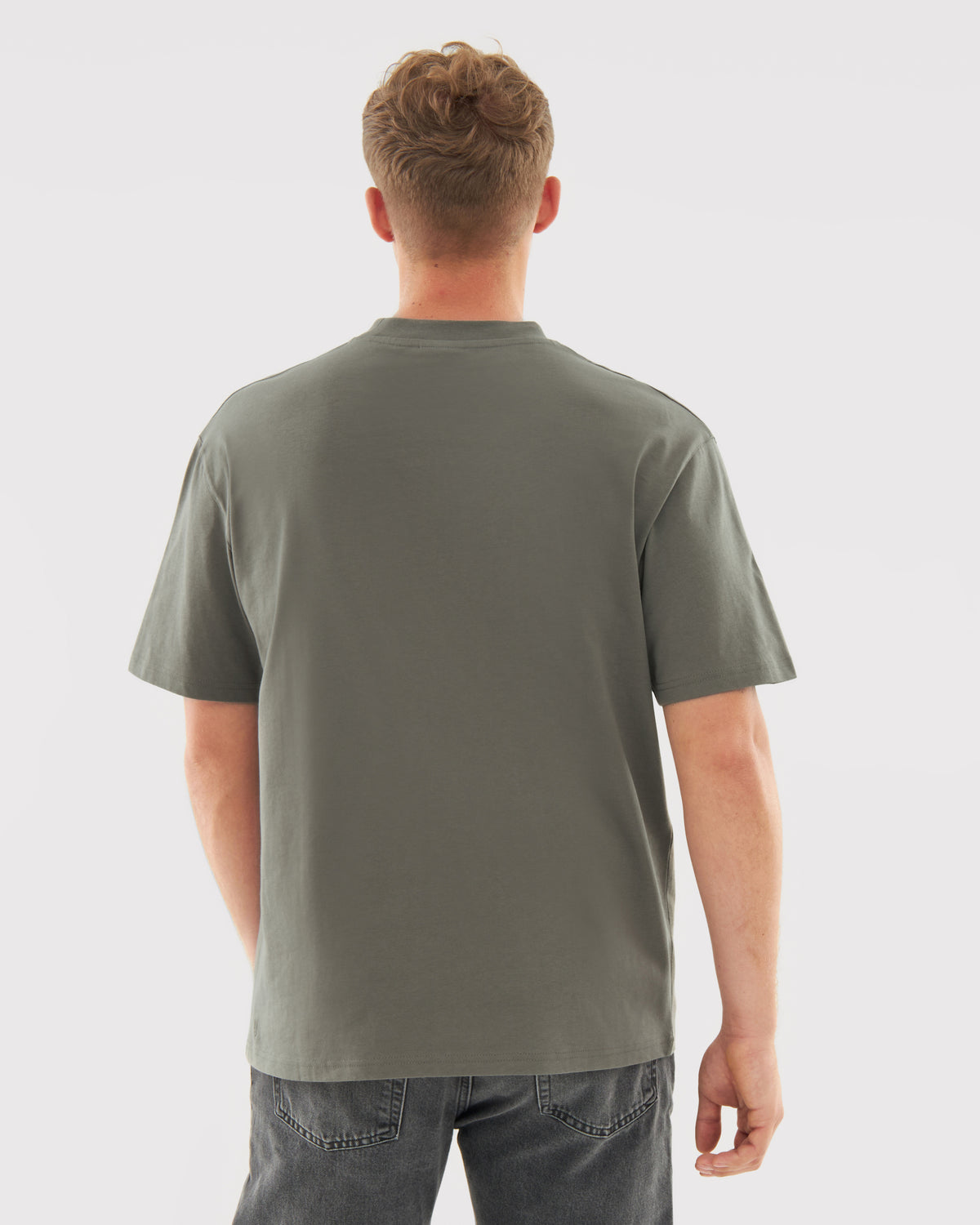 Rückansicht eines Mannes, der ein olivgrünes oversized T-Shirt 'Sammy' und dunkle Jeans trägt