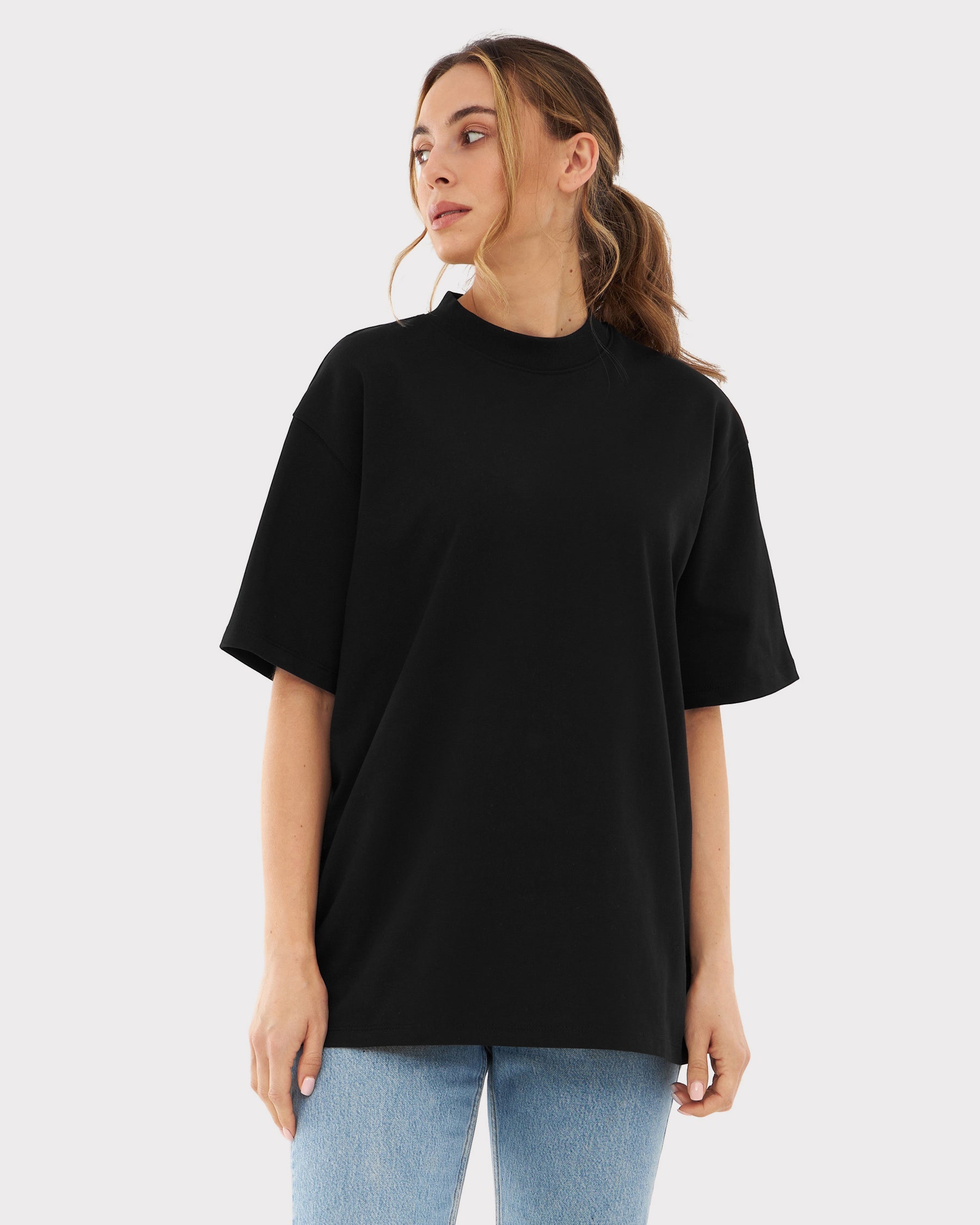 Frau trägt schwarzes Oversize-T-Shirt ohne Aufdruck und blaue Jeans