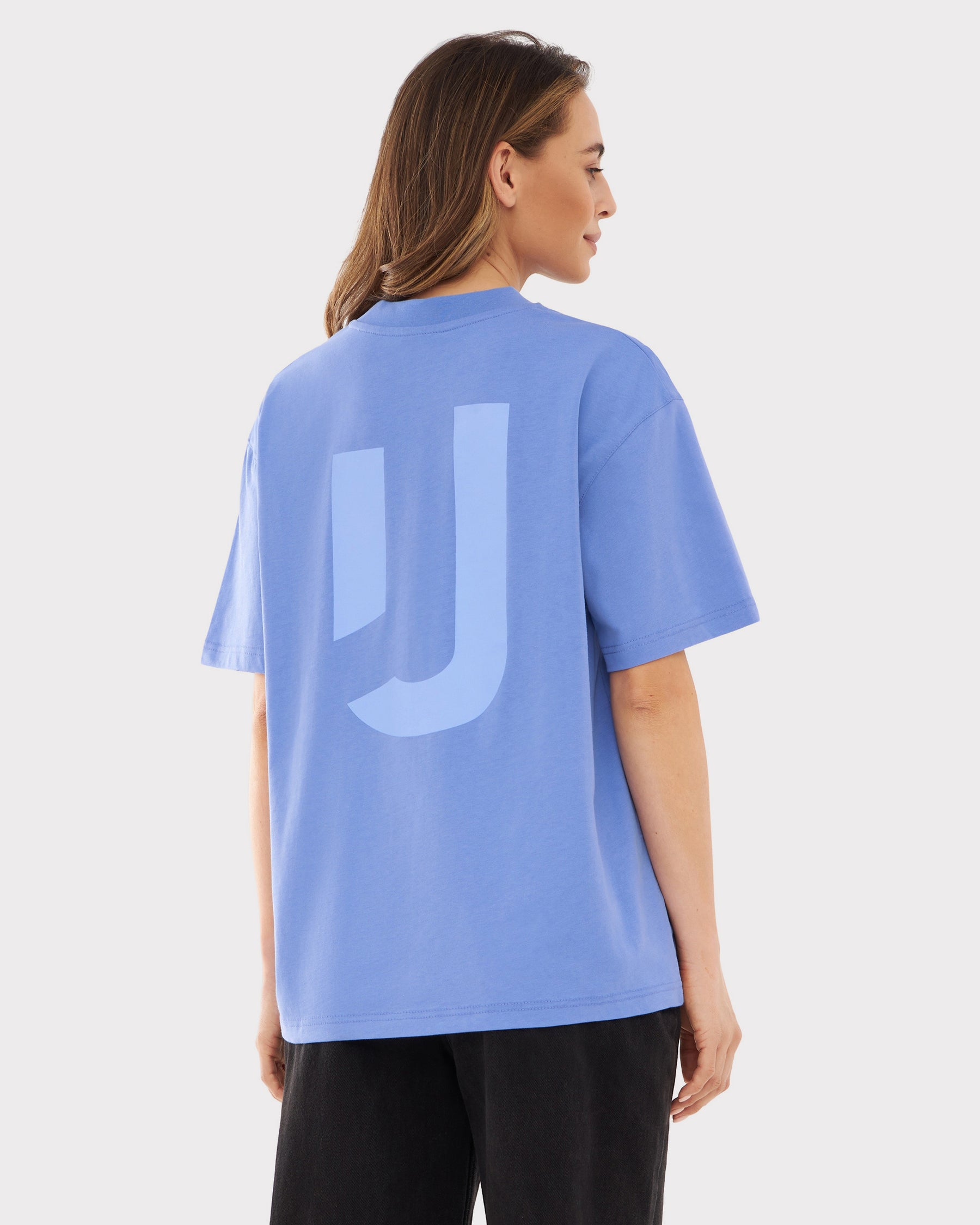 Frau trägt lila-lilafarbenes Oversize-T-Shirt 'Sammy JU' mit großem 'JU' Print auf dem Rücken