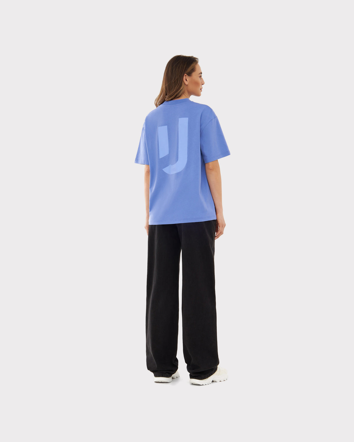 Frau trägt lila Johnny Urban Oversize-T-Shirt 'Sammy JU' mit großem J-Logo auf dem Rücken, schwarze Hose