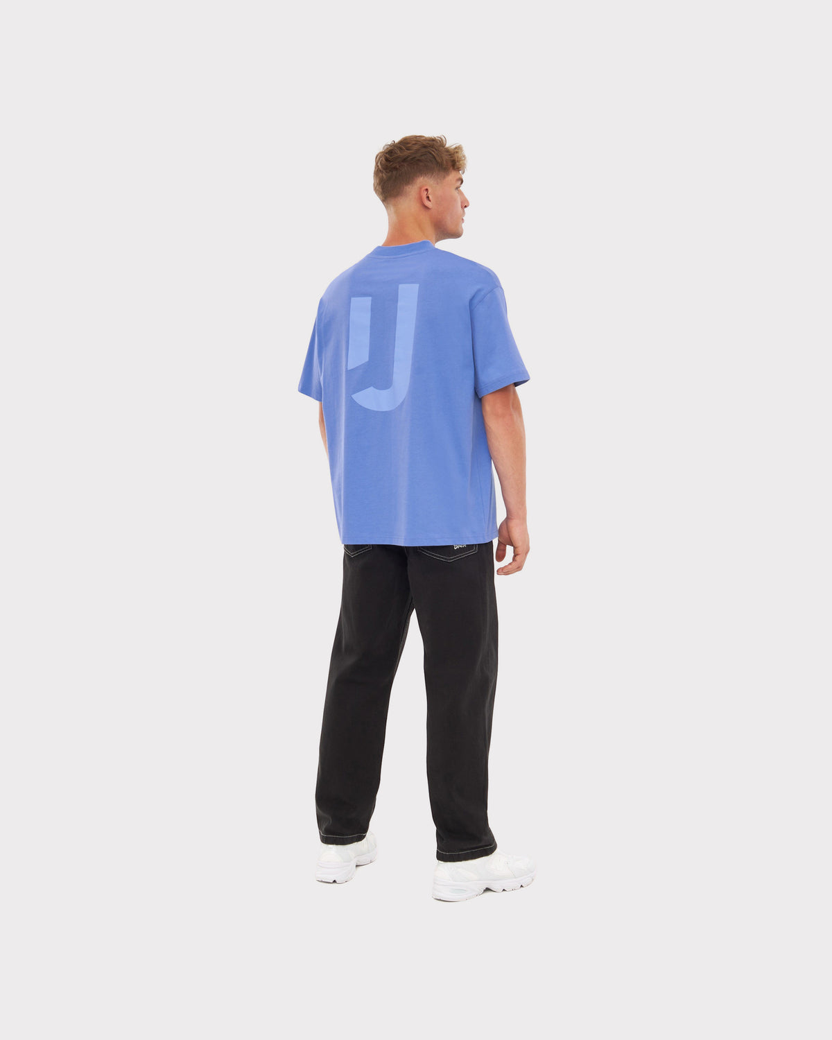 Mann von hinten in oversized blau-lila T-Shirt 'Sammy JU' und schwarzer Hose
