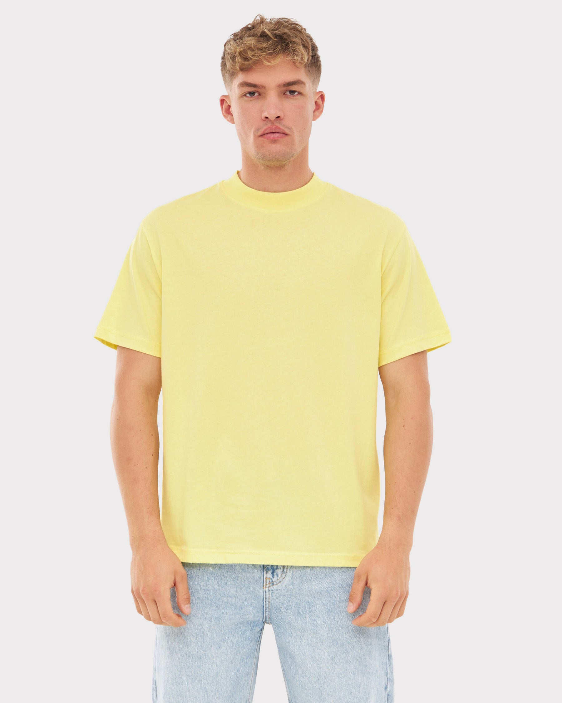 Mann trägt oversized T-Shirt 'Sammy JU' in Gelb, kombiniert mit hellblauen Jeans