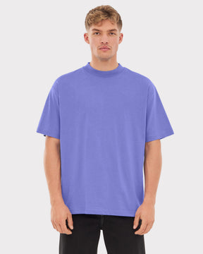 Mann trägt lila oversize T-Shirt ohne Aufdruck, steht frontal, trägt schwarze Hose