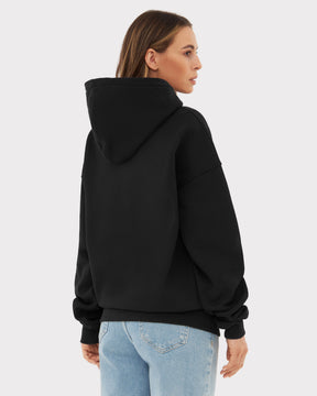 Rückansicht einer Frau mit schwarzem übergroßen Hoodie 'Cody' von Johnny Urban und hellblauen Jeans
