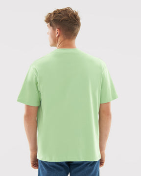 Mann trägt oversized T-Shirt 'Sammy' in Salbeigrün, Rückansicht, kombiniert mit blauer Jeans