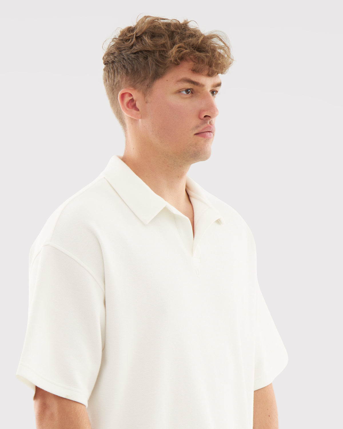 Mann trägt cremefarbenes Herren-Poloshirt mit kurzem Arm und offenem Kragen