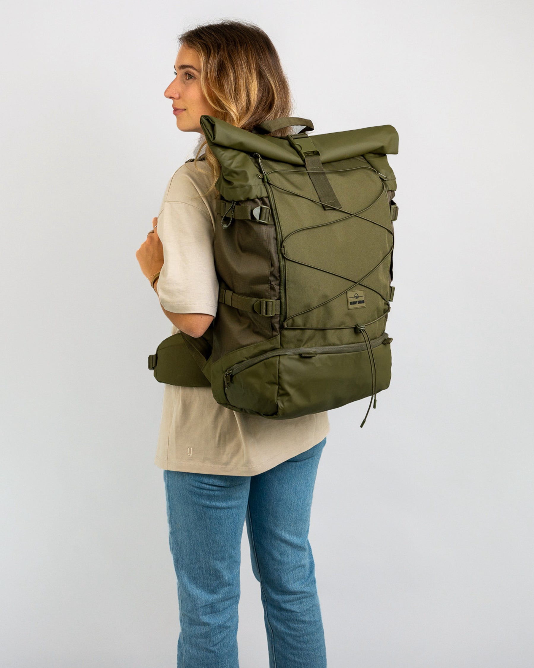 Frau trägt olivgrünen Reiserucksack 'Allen XL Travel' von Johnny Urban mit Rollverschluss und Hüftgurt