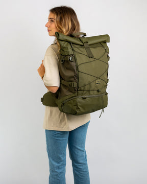 Frau trägt olivgrünen Reiserucksack 'Allen XL Travel' von Johnny Urban mit Rollverschluss und Hüftgurt