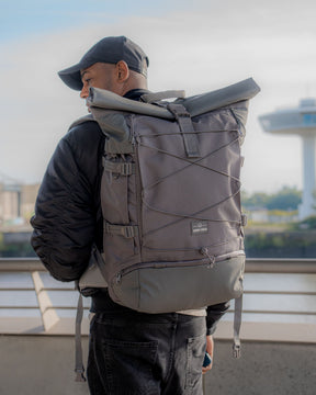Mann trägt grauen Johnny Urban Reiserucksack 'Allen XL Travel' mit Rollverschluss und Außenspannbändern