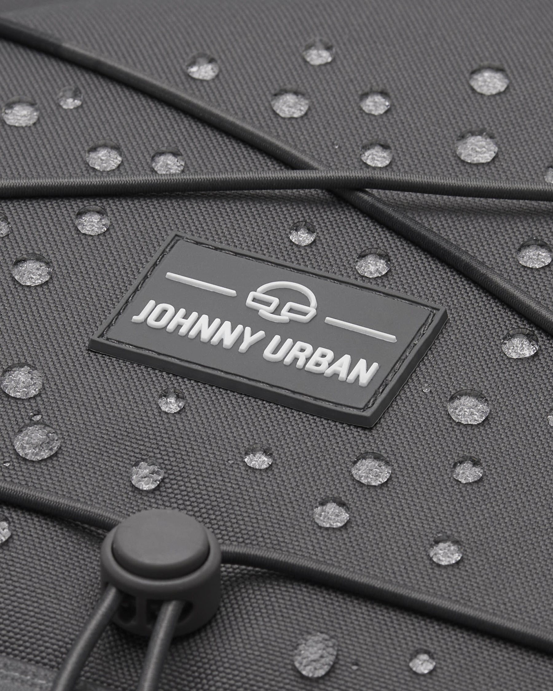 Nahaufnahme des grauen Johnny Urban Reiserucksacks 'Allen XL Travel' mit Wassertröpfchen auf dem Material