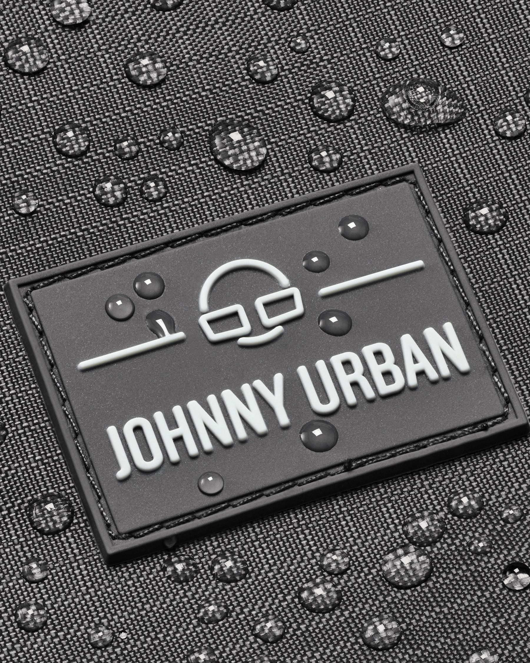 Nahaufnahme des wasserabweisenden Johnny Urban Logos auf dem Rucksack 'Jack' in dunkelgrauem Stoff