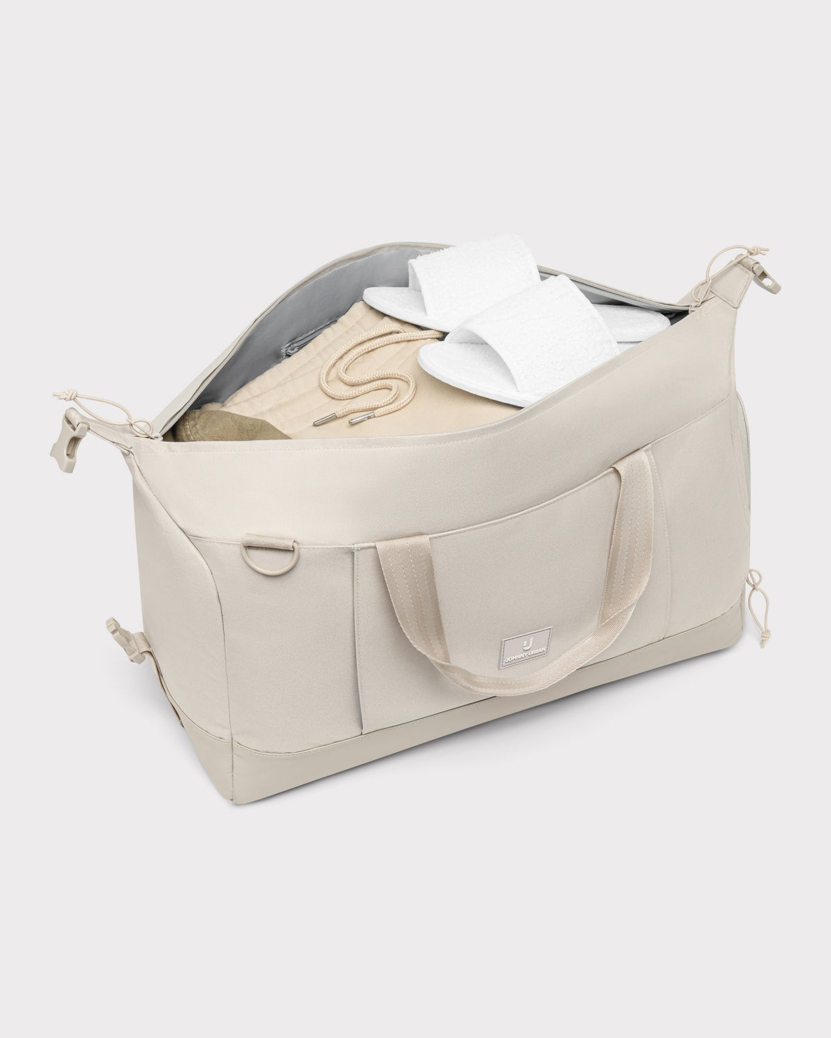 Sandfarbene Weekender-Reisetasche 'Milan' von Johnny Urban, gefüllt mit Kleidung und weißen Hausschuhen
