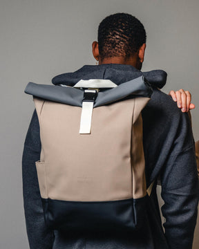 Rolltop Rucksack "Harvey Medium" in Beige mit grauem Verschluss an einem Mann von hinten