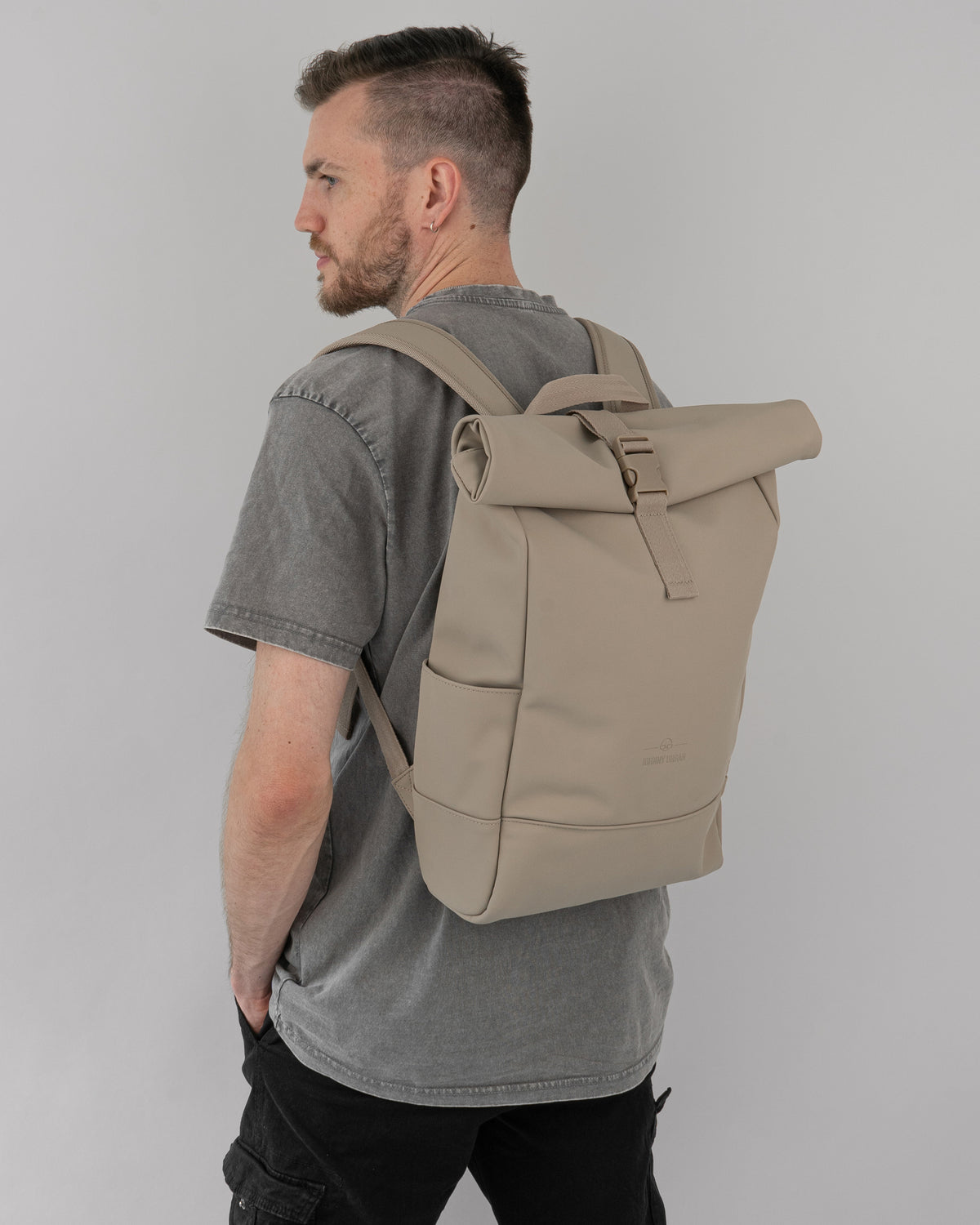 Mann mit grauem T-Shirt und beigem Rolltop Rucksack 'Harvey Medium' von Johnny Urban
