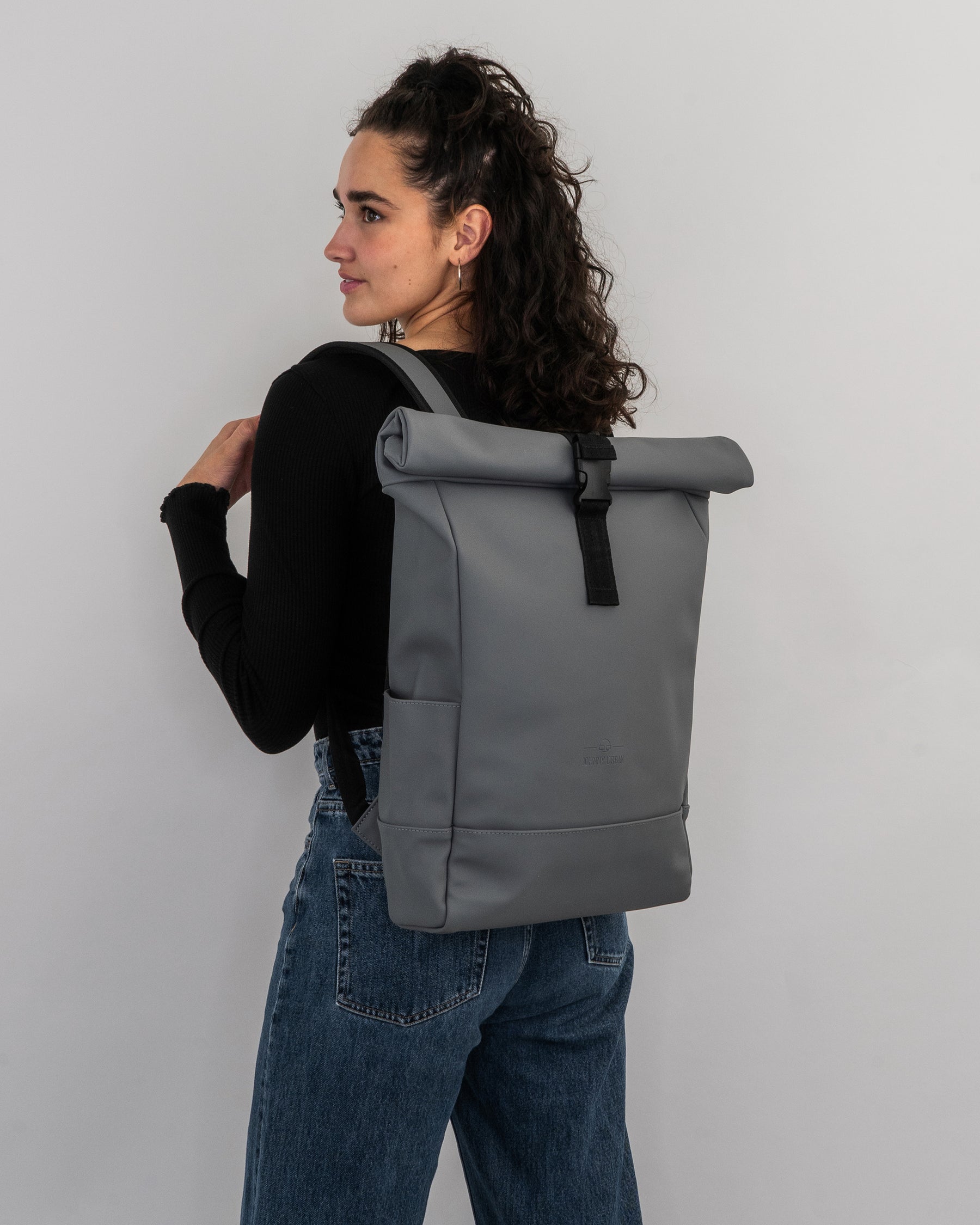 Frau trägt grauen Rolltop Rucksack 'Harvey Medium' mit schwarzem Verschluss und Trägern