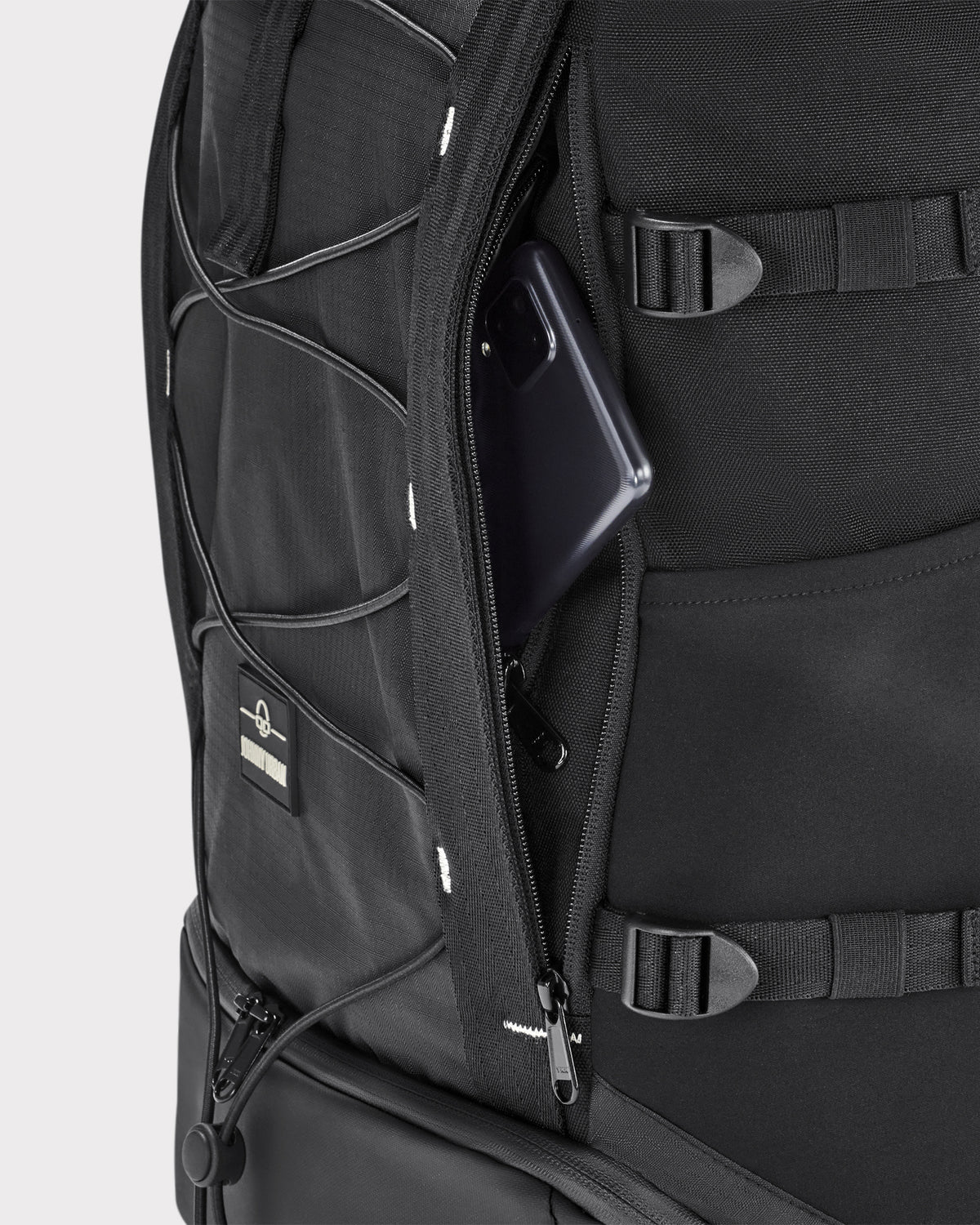 Schwarzer Rolltop Rucksack 'Allen Large Move' mit geöffnetem Geheimfach, in dem ein Smartphone steckt