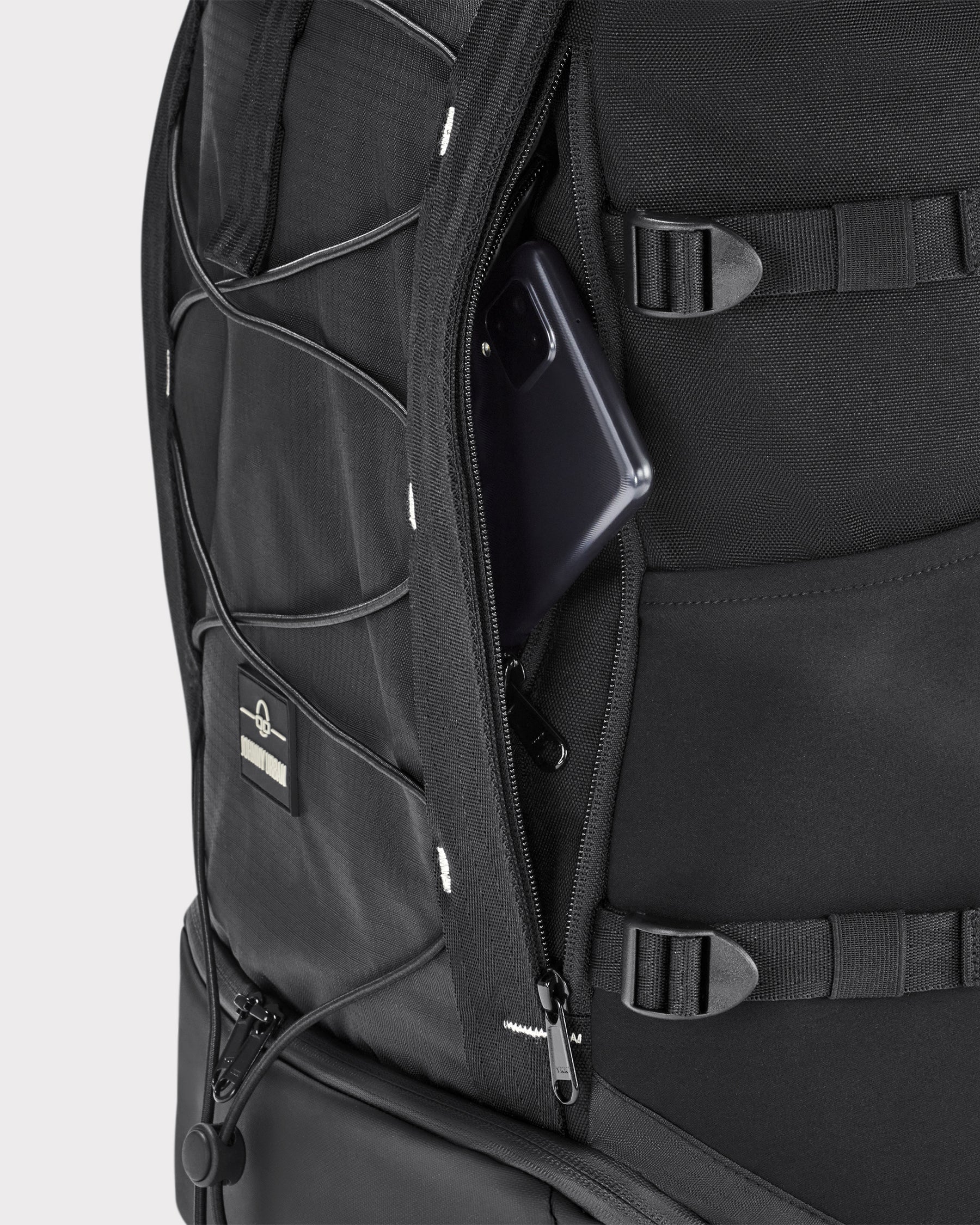 Schwarzer Rolltop Rucksack 'Allen Large Move' mit geöffnetem Geheimfach, in dem ein Smartphone steckt