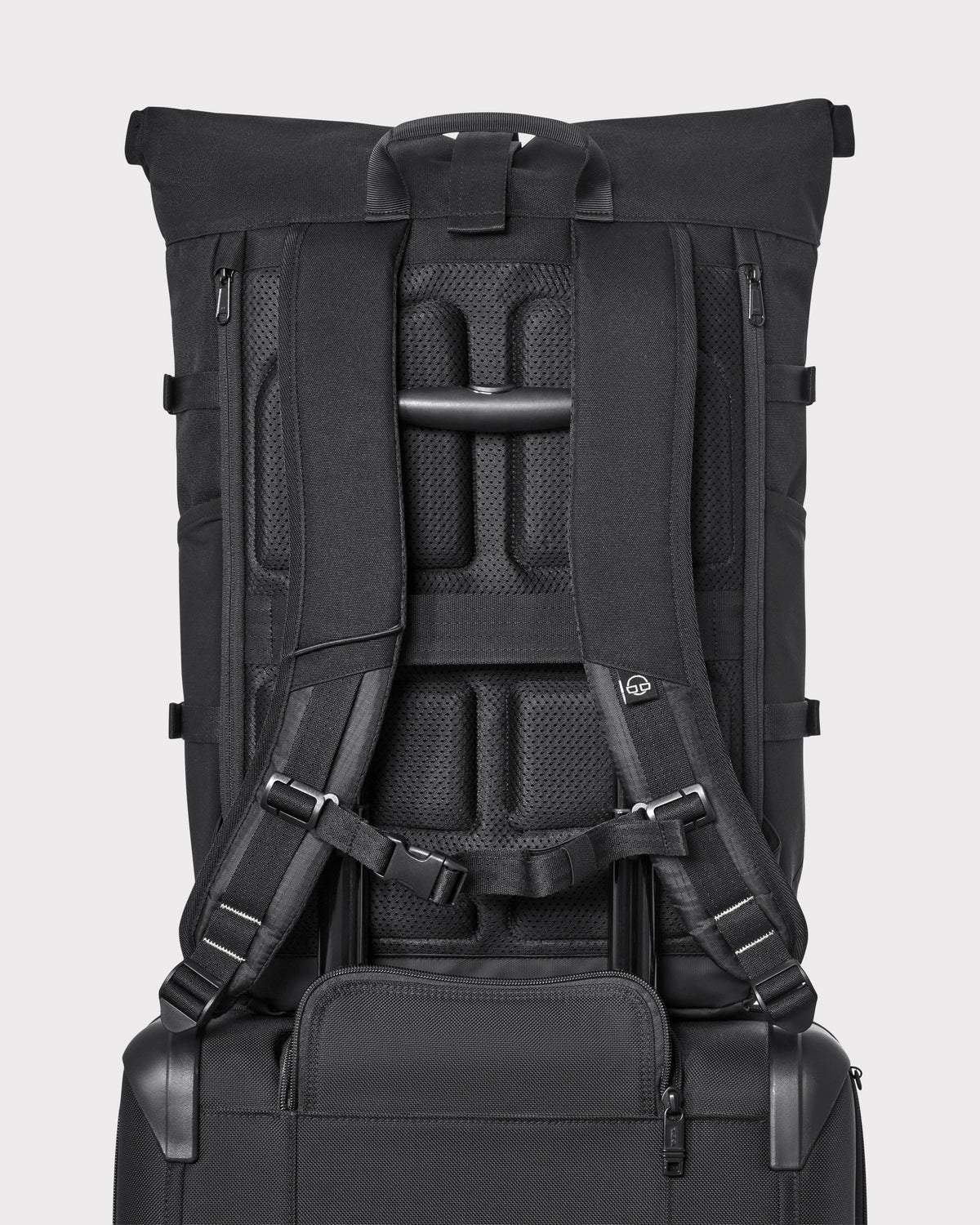 Rückansicht des schwarzen Rolltop-Rucksacks 'Allen Large Move' mit gepolsterten Schultergurten und Halterung auf schwarzem Trolleygriff