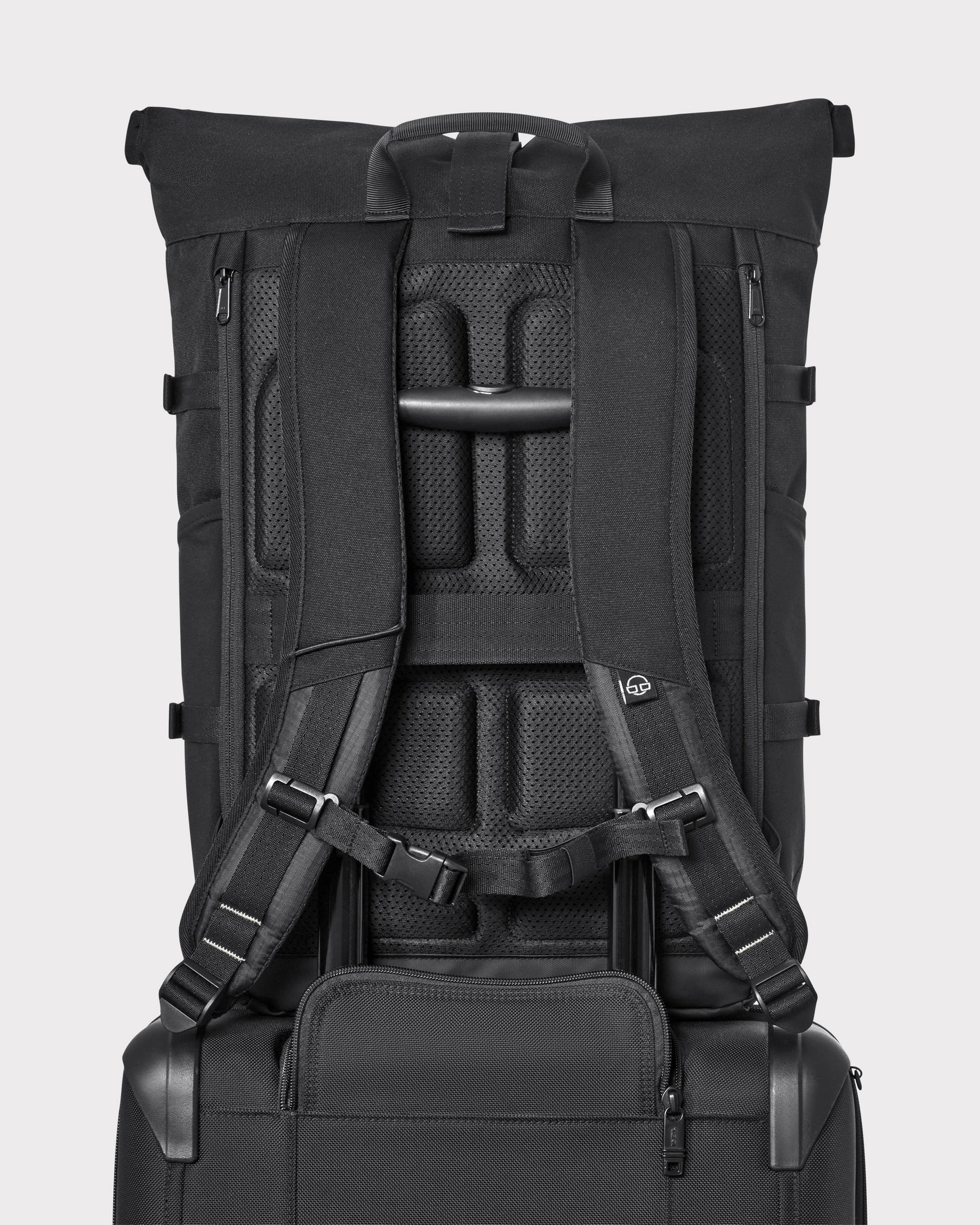 Rückansicht des schwarzen Rolltop-Rucksacks 'Allen Large Move' mit gepolsterten Schultergurten und Halterung auf schwarzem Trolleygriff