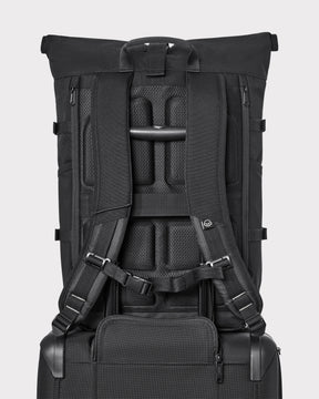 Rückansicht des schwarzen Rolltop-Rucksacks 'Allen Large Move' mit gepolsterten Schultergurten und Halterung auf schwarzem Trolleygriff