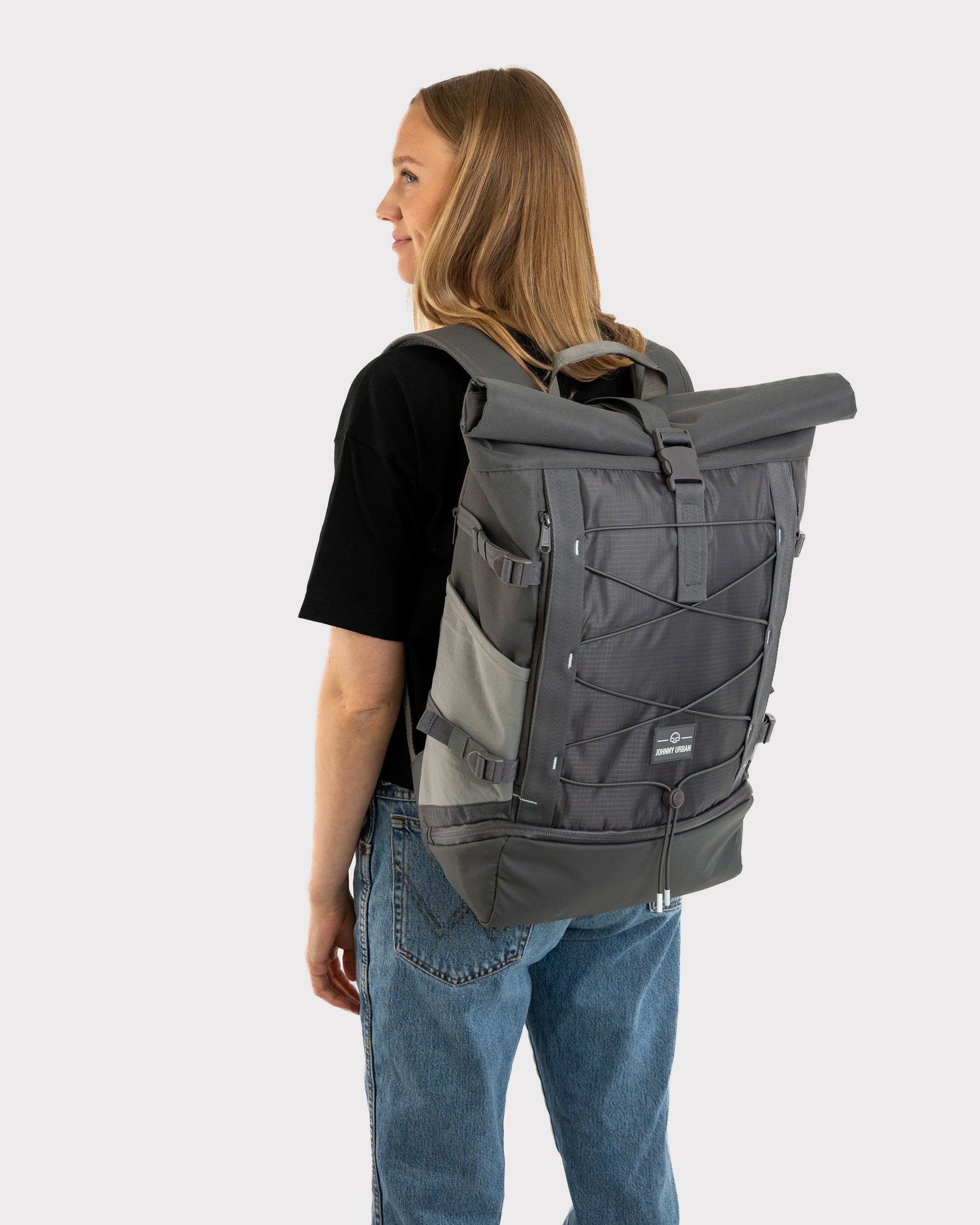 Frau mit schwarzem T-Shirt und Jeans trägt grauen Rolltop Rucksack 'Allen Large Move' von Johnny Urban